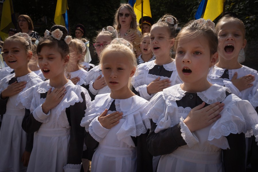 Schoolgirls sing the national anthem on the first day at school in a cadet lyceum in Kyiv, Ukraine, Monday, Sept. 2, 2024. Children and students went to school despite the fact that Kyiv was hit by massive Russian missile barrage early in the morning, causing fires, damaged buildings and infrastructure objects. (AP Photo/Efrem Lukatsky)