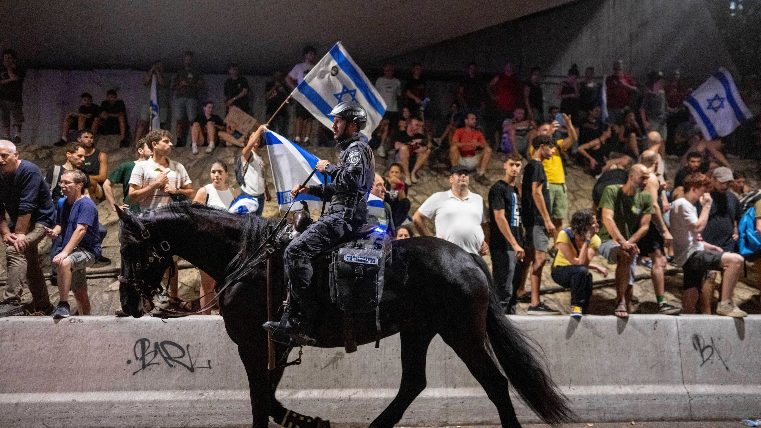 A police officer on a horse moves past a protest calling for a deal for the immediate release of hostages held in the Gaza Strip by Hamas, in Tel Aviv, Israel, Sunday, Sept. 1, 2024. (AP Photo/Ohad Zwigenberg)