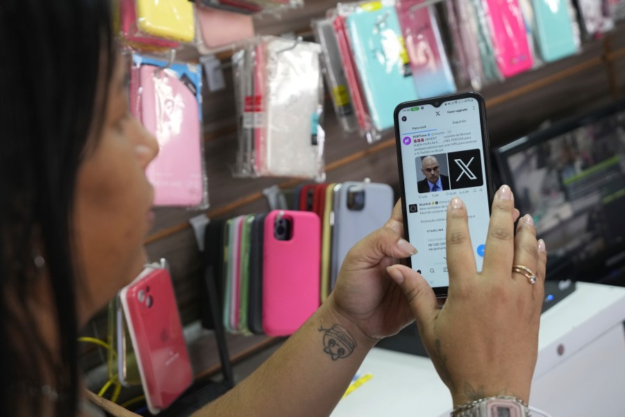 Ana Claudia, a salesperson at a cell phone case store located inside the bus station, shows the last X post she received before the social media platform was blocked nationwide in Brasilia, Brazil, Monday, Sept. 2, 2024. (AP Photo/Eraldo Peres)