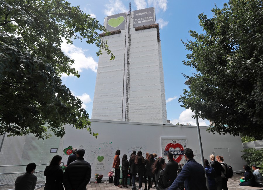 FILE - People pay their respects at the Grenfell tower to mark the two-year anniversary of the Grenfell Tower block fire, in London, Friday, June 14, 2019. (AP Photo/Frank Augstein, File)