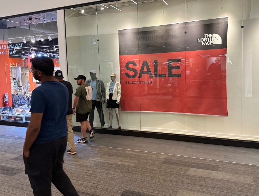 FILE - Shoppers pass a sign trumpeting sales at an outlet mall Wednesday, Sept. 11, 2024, in Lakewood, Colo. (AP Photo/David Zalubowski, File)