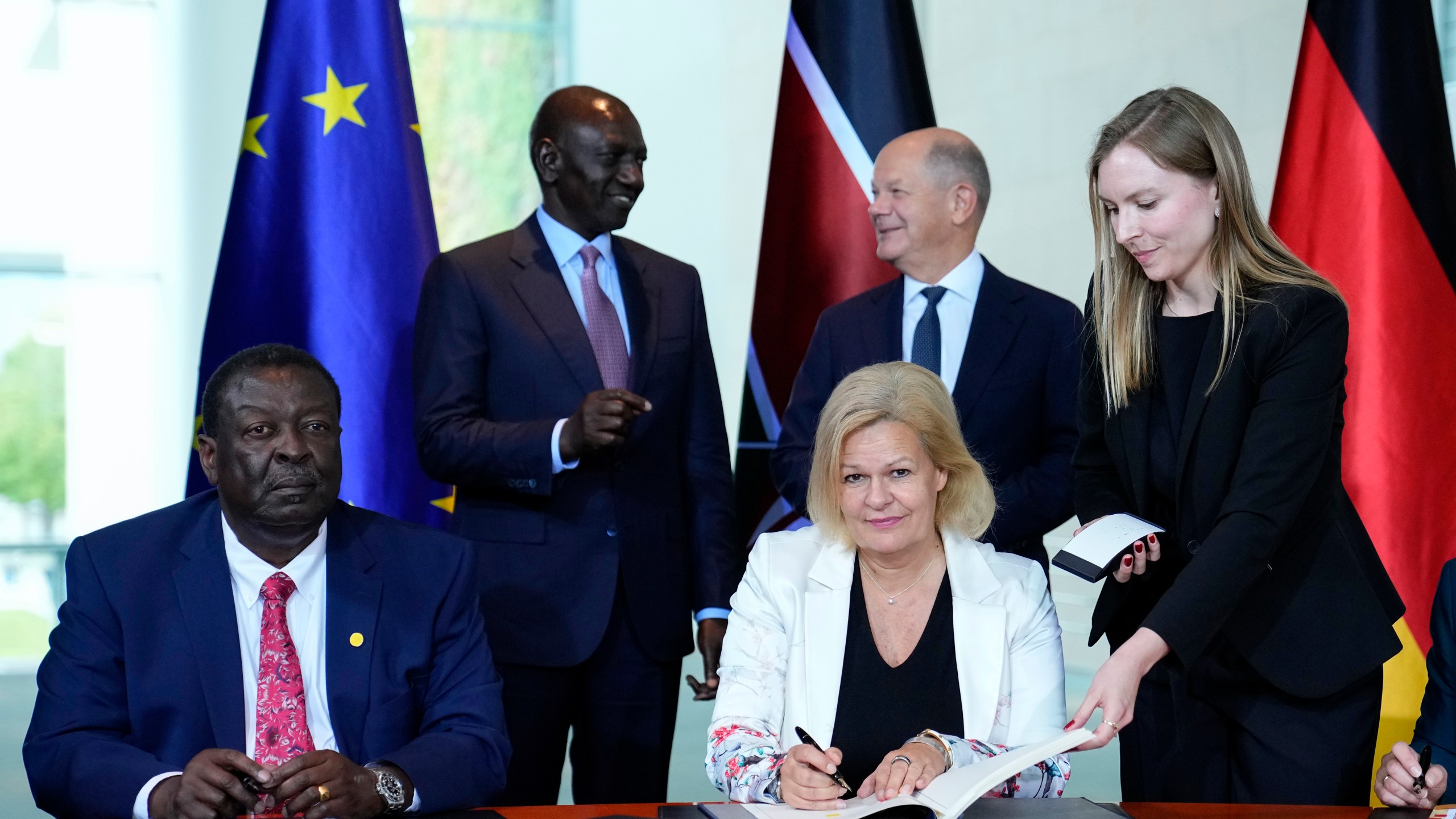 German Interior Minister Nancy Faeser, down right, signs a migration agreement with Kenyan's Prime Cabinet Secretary Musalia Mudavadi, left, as German Chancellor Olaf Scholz, centre behind, and Kenyan President William Ruto, left behind, at the chancellery in Berlin, Friday, Sept. 13, 2024. (AP Photo/Ebrahim Noroozi)