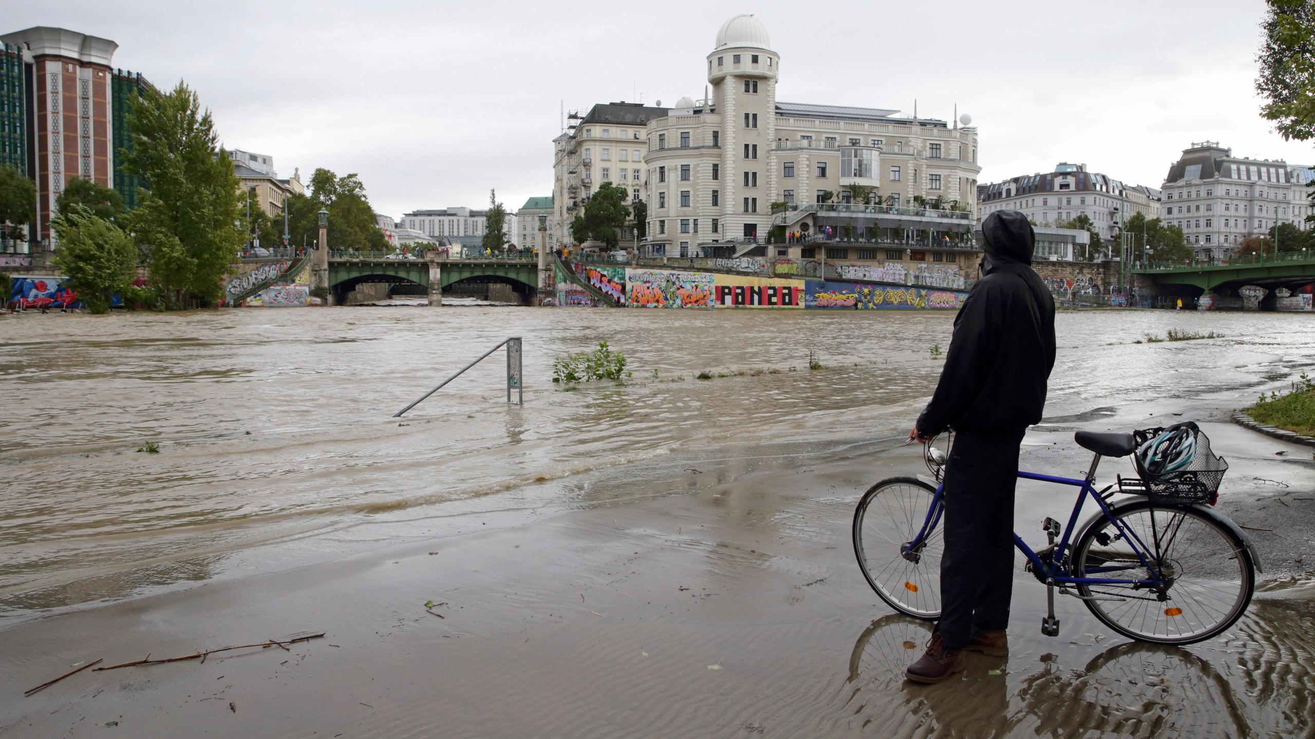 A cyclist looks at Donaukanal channel flood its banks at Urania observatory in central Vienna, Austria, Sunday, Sept. 15, 2024. (AP Photo/Heinz-Peter Bader)