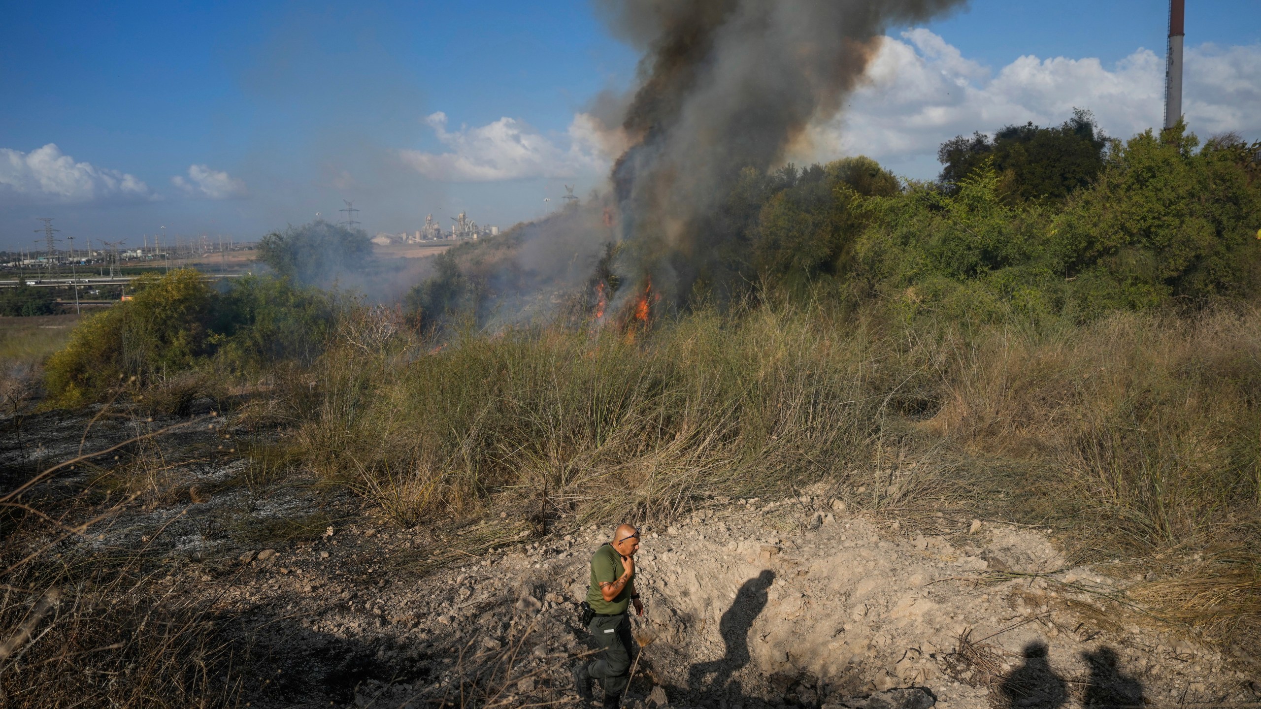 A police officer inspects the area around a fire after the military said it fired interceptors at a missile launched from Yemen that landed in central Israel on Sunday, Sept. 15, 2024. (AP Photo/Ohad Zwigenberg)