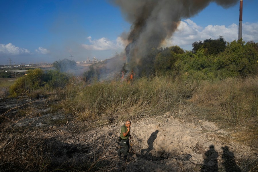 A police officer inspects the area around a fire after the military said it fired interceptors at a missile launched from Yemen that landed in central Israel on Sunday, Sept. 15, 2024. (AP Photo/Ohad Zwigenberg)