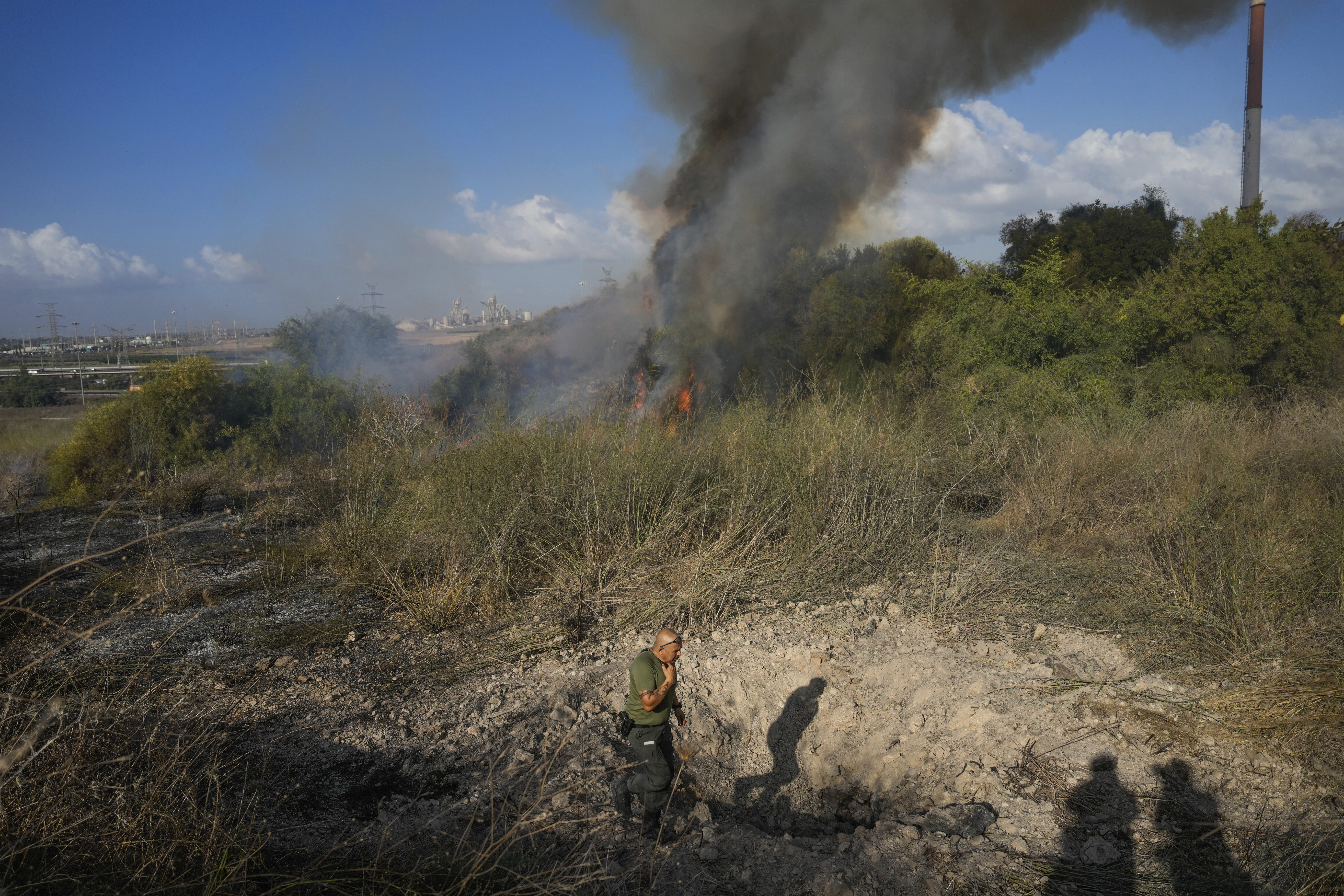 A police officer inspects the area around a fire after the military said it fired interceptors at a missile launched from Yemen that landed in central Israel on Sunday, Sept. 15, 2024. (AP Photo/Ohad Zwigenberg)