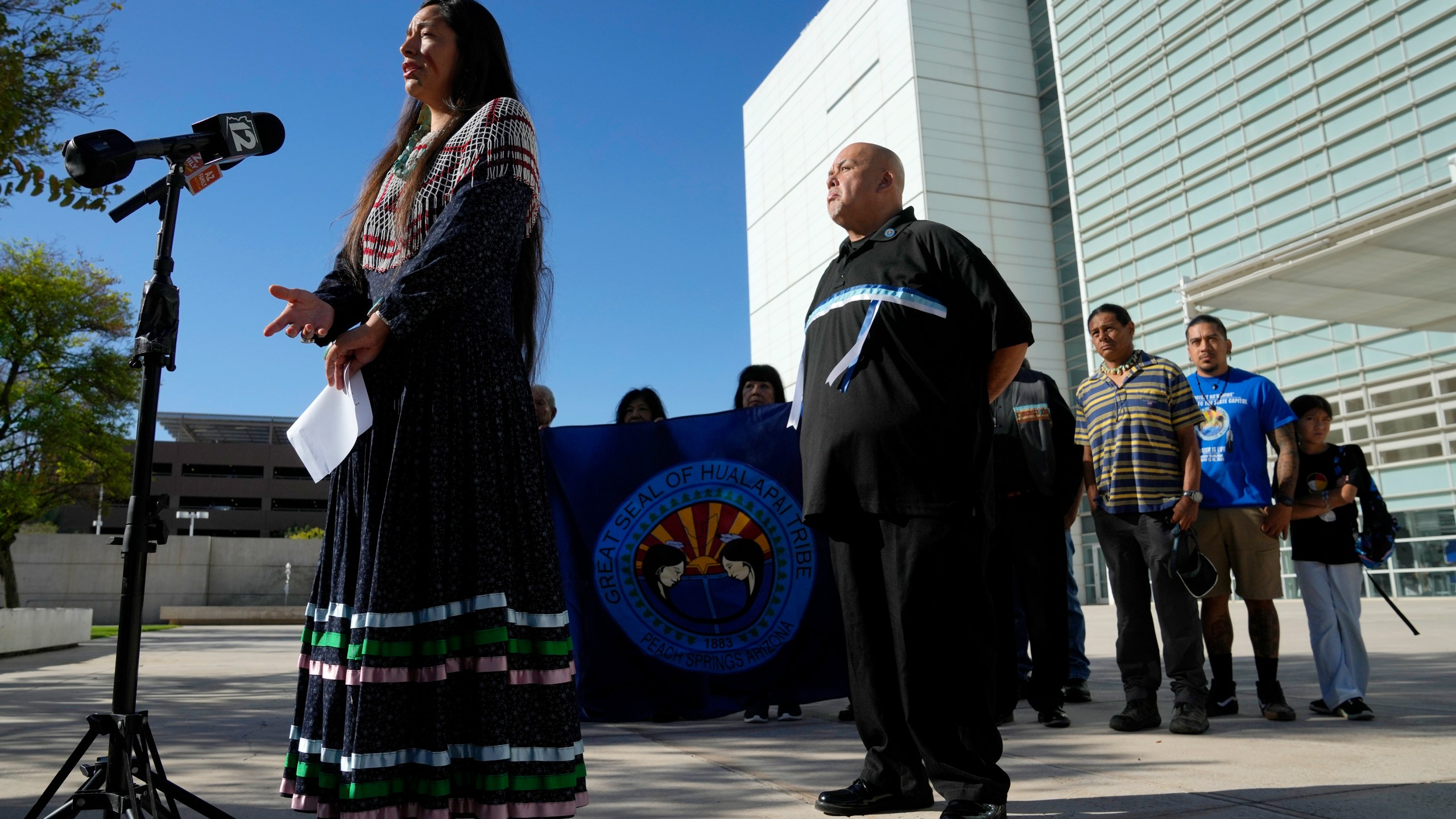 Ka-Voka Jackson, left, director of cultural resources for the Hualalpai Tribe, speaks during a news conference in front of U.S. District Court as she joins other members of the Hualapai Tribe, including Duane Clark, chairman of the Hualapai Tribe, as they gathered to try to persuade a federal judge to extend a temporary ban on exploratory drilling for a lithium project Tuesday, Sept. 17, 2024, in Phoenix. (AP Photo/Ross D. Franklin)