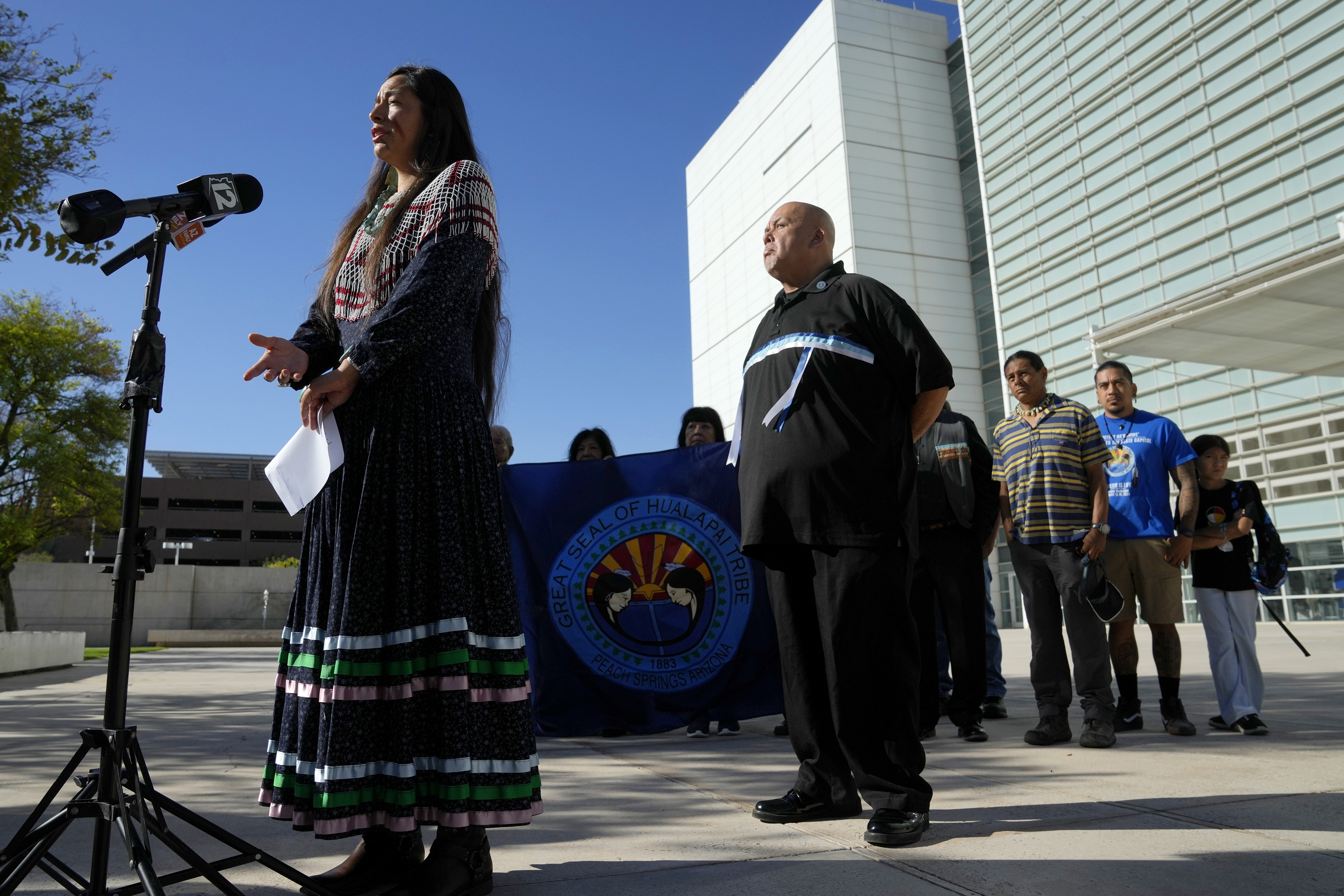 Ka-Voka Jackson, left, director of cultural resources for the Hualalpai Tribe, speaks during a news conference in front of U.S. District Court as she joins other members of the Hualapai Tribe, including Duane Clark, chairman of the Hualapai Tribe, as they gathered to try to persuade a federal judge to extend a temporary ban on exploratory drilling for a lithium project Tuesday, Sept. 17, 2024, in Phoenix. (AP Photo/Ross D. Franklin)