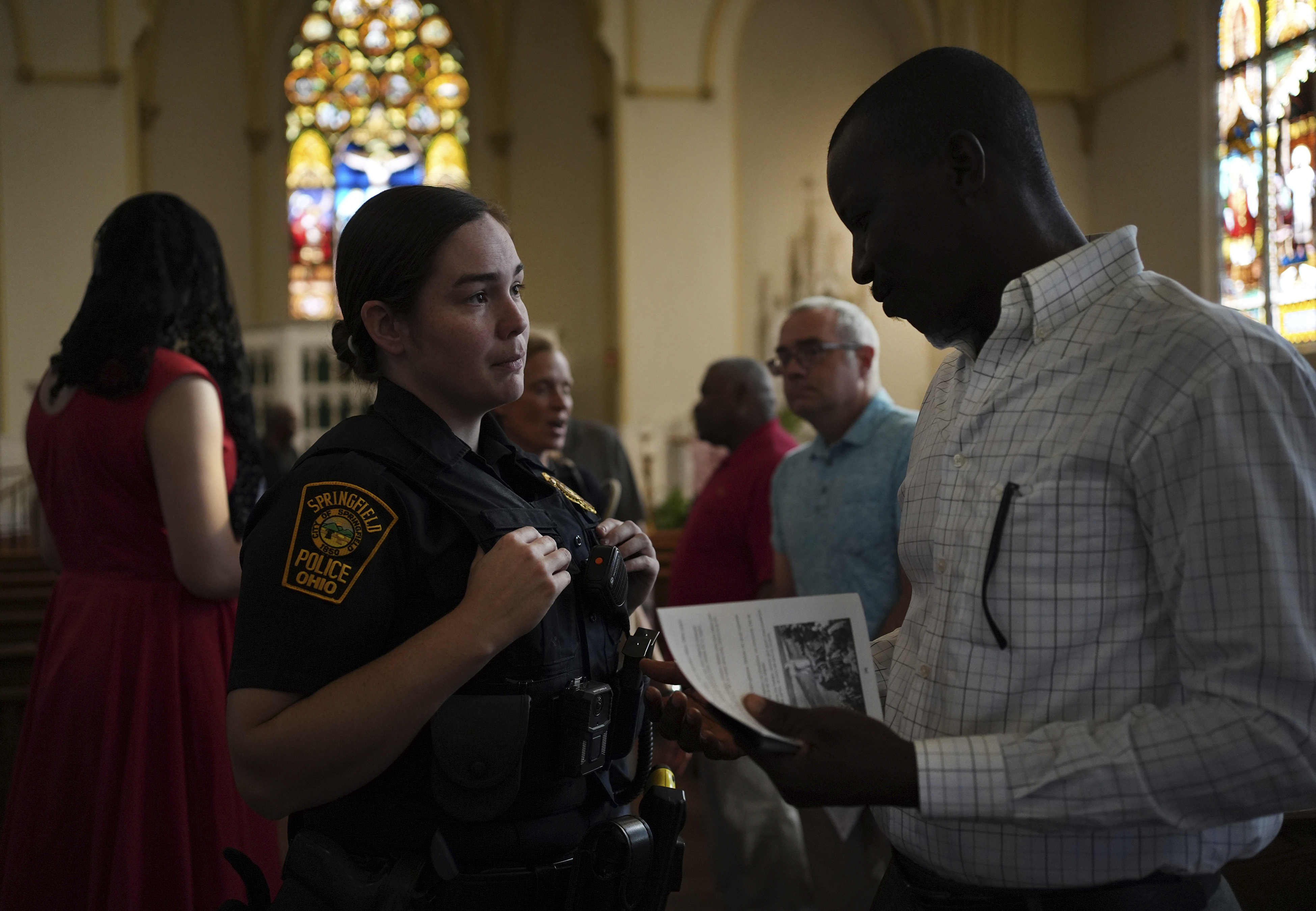 A Springfield police officer talks to a parishioner after a service in support of the Haitian community at St. Raphael Catholic church in Springfield, Ohio, Sunday, Sept. 15, 2024. (AP Photo/Luis Andres Henao)