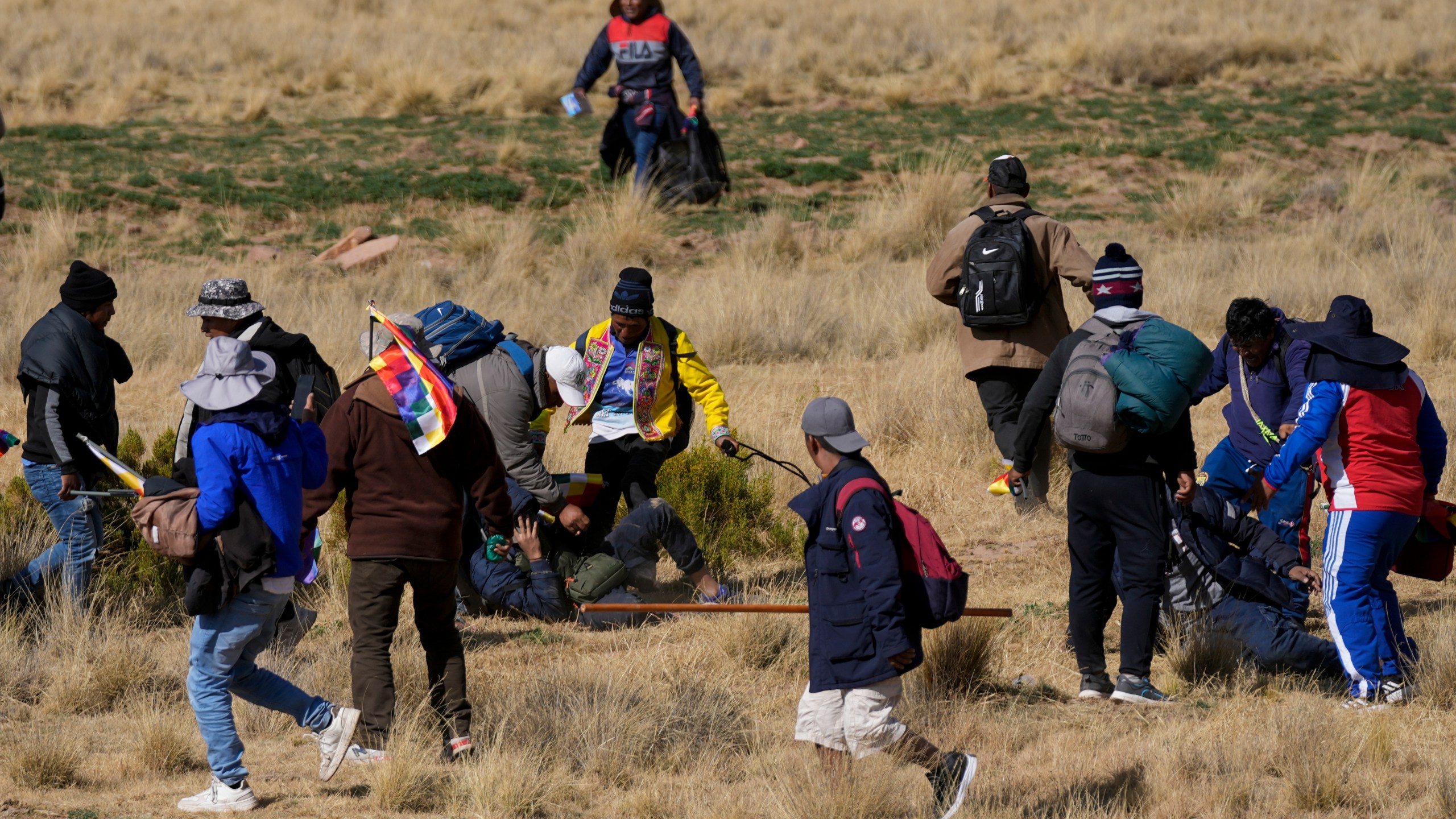 Supporters of former President Evo Morales kick a government supporter whose group confronted them in Vila Vila, Bolivia, during their march to the capital, Tuesday, Sept. 17, 2024. Morales and his supporters are marching to the capital to protest the government of President Luis Arce in an escalation of a political dispute between the two politicians. (AP Photo/Juan Karita)