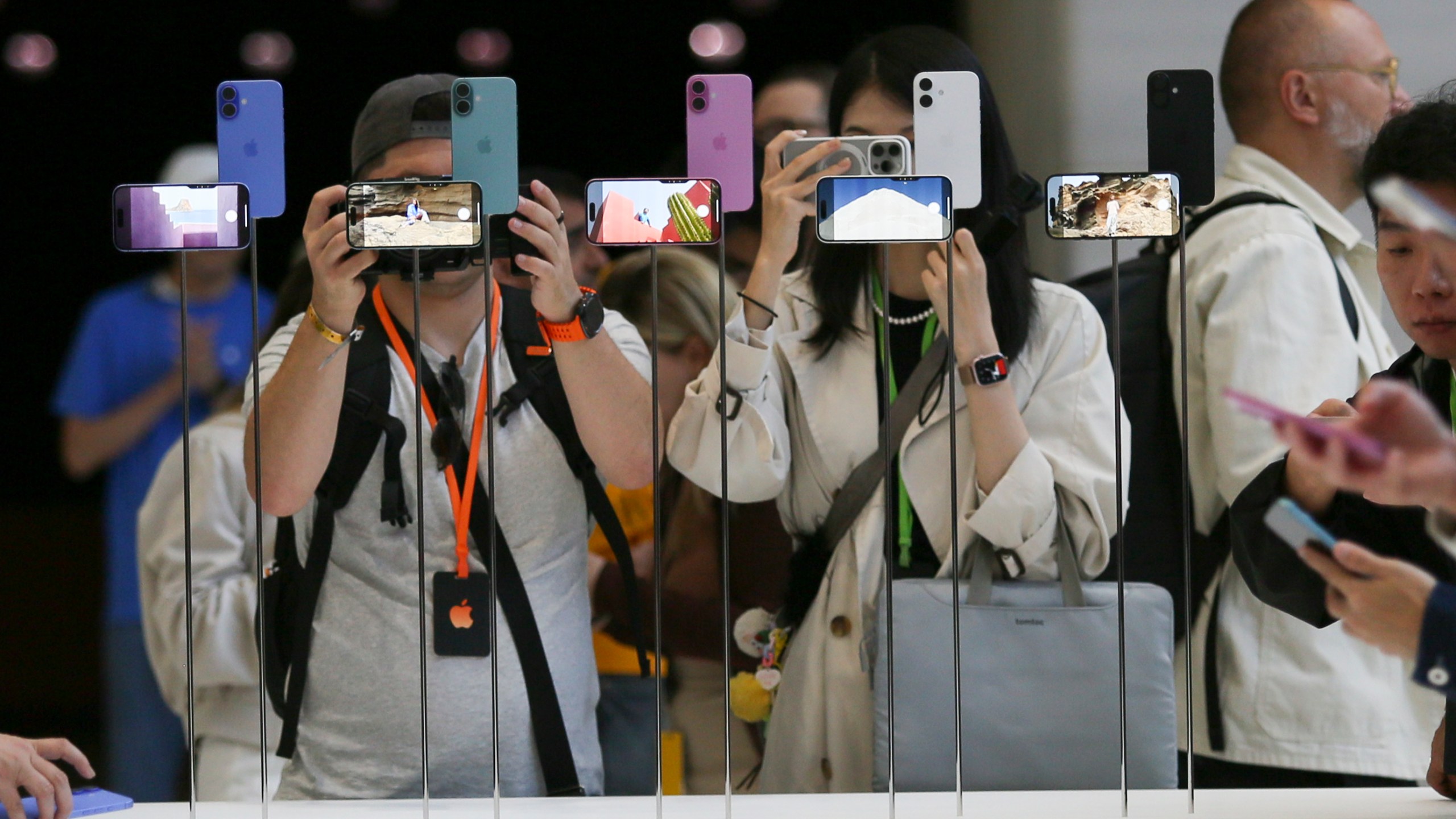 Attendees take a closer look at the Apple iPhone 16 during an announcement of new products at Apple headquarters Monday, Sept. 9, 2024, in Cupertino, Calif. (AP Photo/Juliana Yamada)