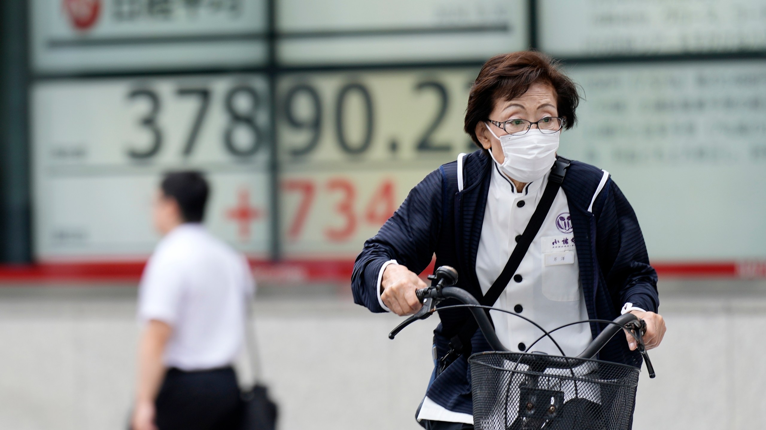 A person rides a bicycle in front of an electronic stock board showing Japan's Nikkei index at a securities firm Friday, Sept. 20, 2024, in Tokyo. (AP Photo/Eugene Hoshiko)