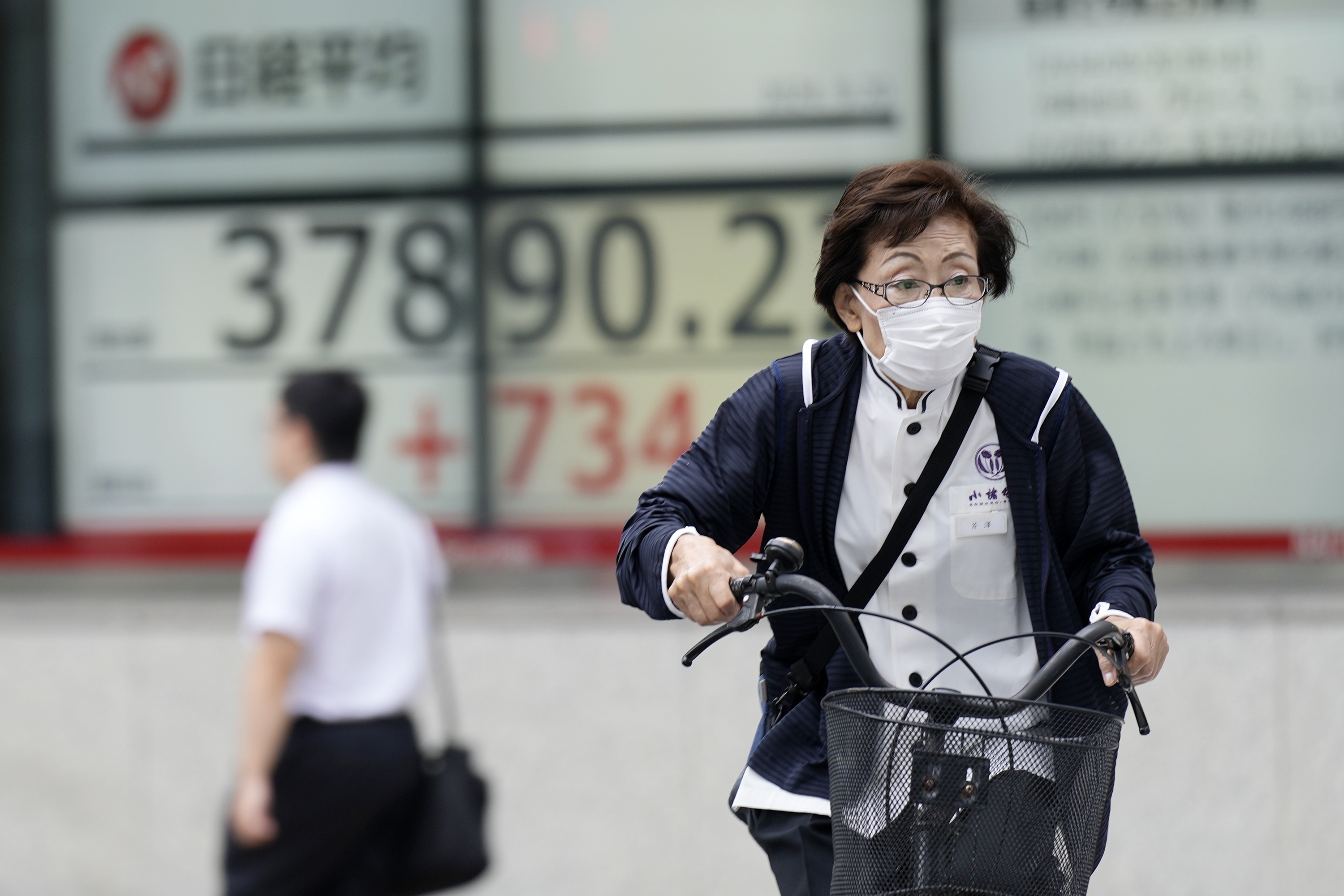 A person rides a bicycle in front of an electronic stock board showing Japan's Nikkei index at a securities firm Friday, Sept. 20, 2024, in Tokyo. (AP Photo/Eugene Hoshiko)