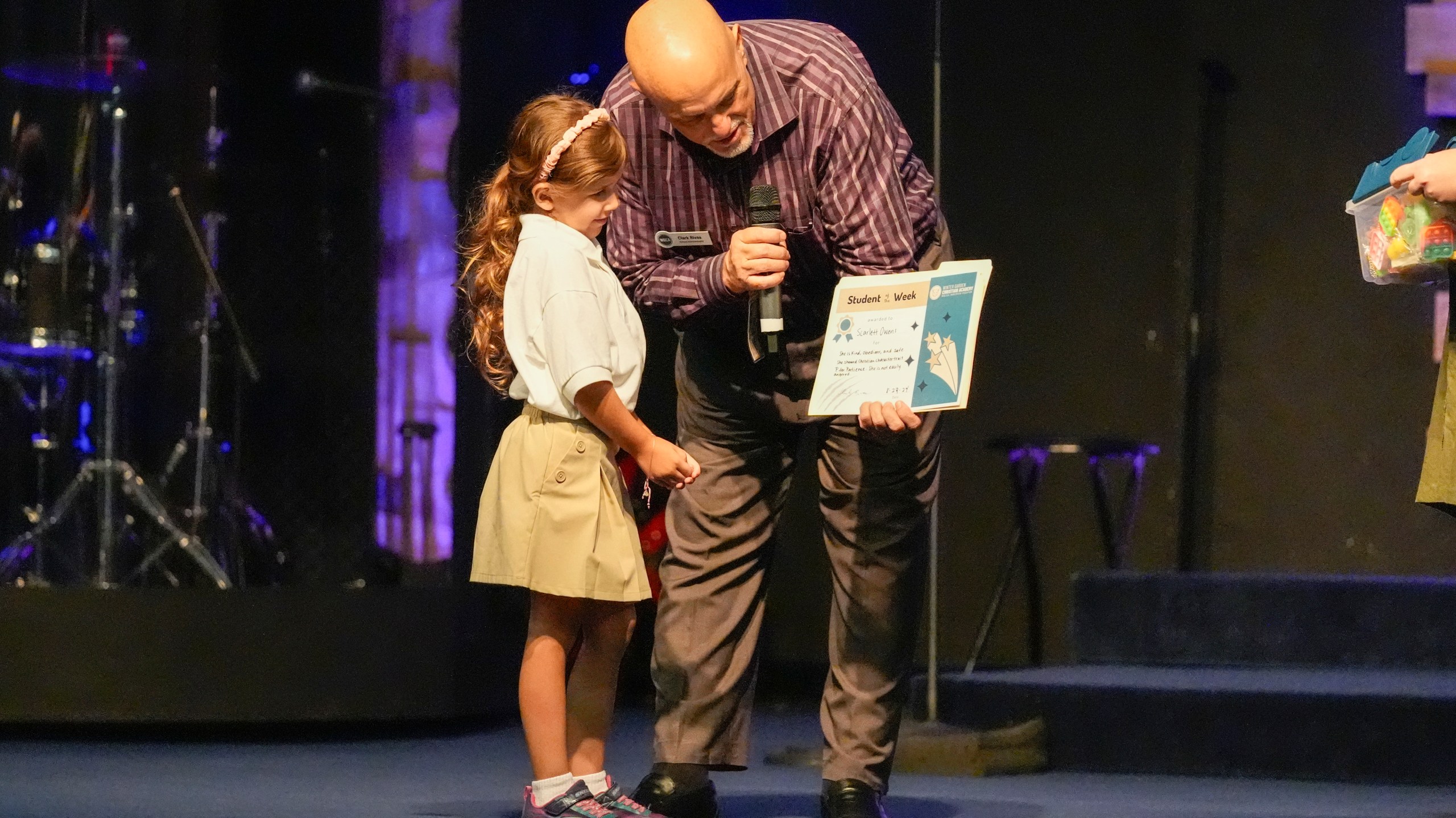 Academy Administrator Clark Rivas, right, presents kindergartner Scarlet Owens, a certificate after she was named student of the week at the Winter Garden Christian Academy Thursday, Aug. 29, 2024, in Winter Garden, Fla. (AP Photo/John Raoux)