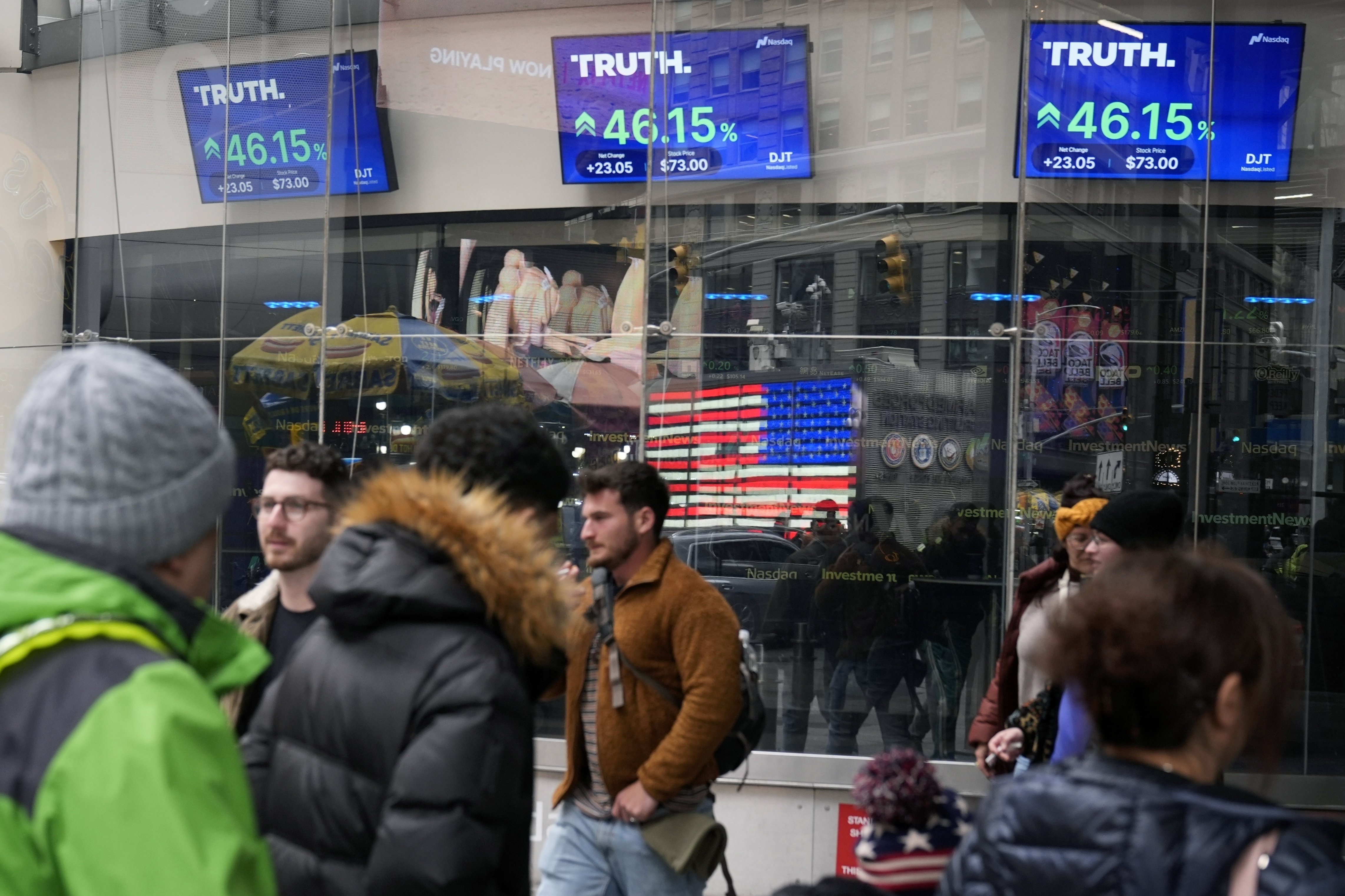 FILE - Pedestrians walk past the Nasdaq building as the stock price of Trump Media & Technology Group Corp. is displayed on screens, March 26, 2024, in New York. (AP Photo/Frank Franklin II, File)