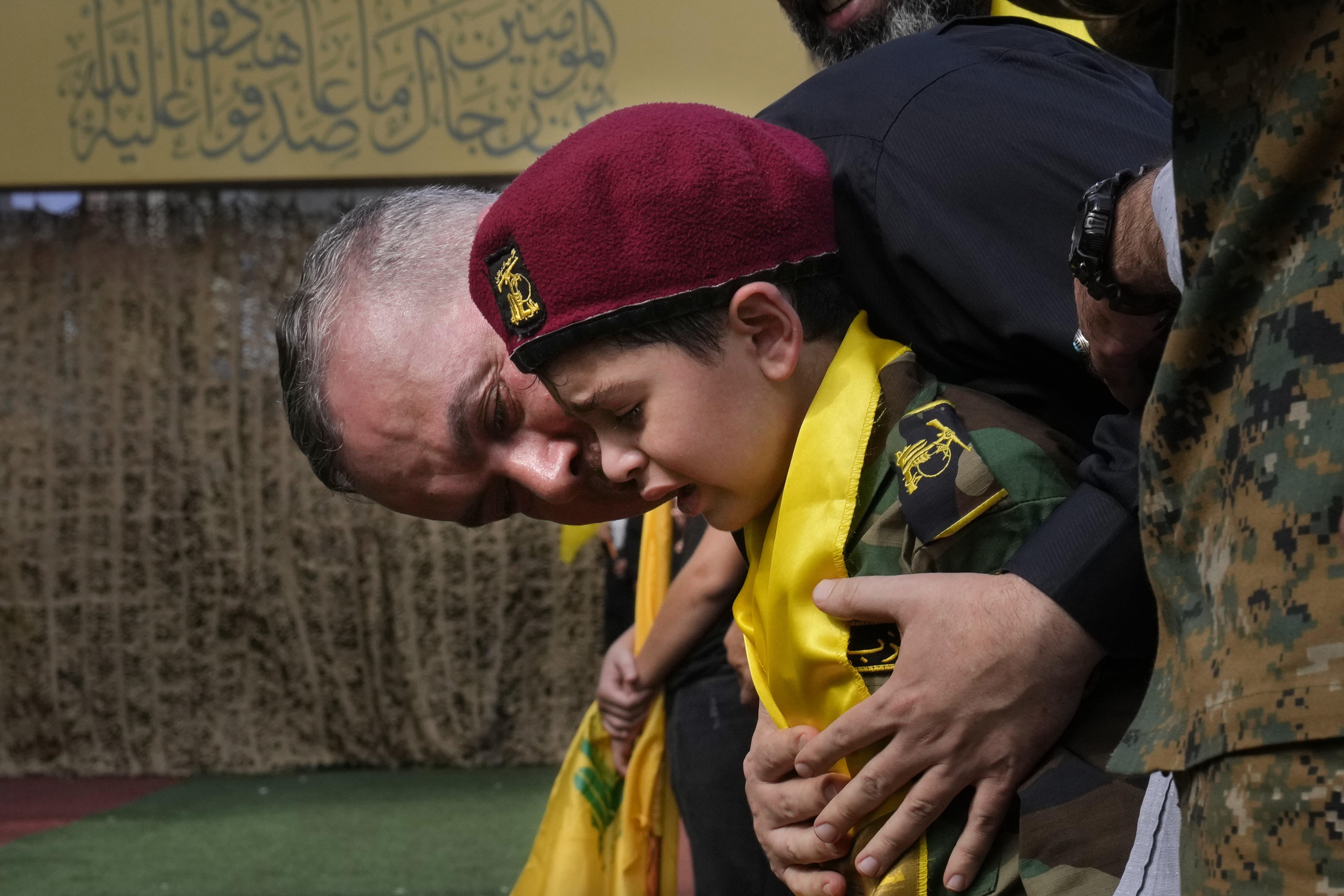 A man comforts a boy crying during the funeral procession of Hezbollah members in the southern suburbs of Beirut, Thursday, Sept. 19, 2024. (AP Photo/Hussein Malla)