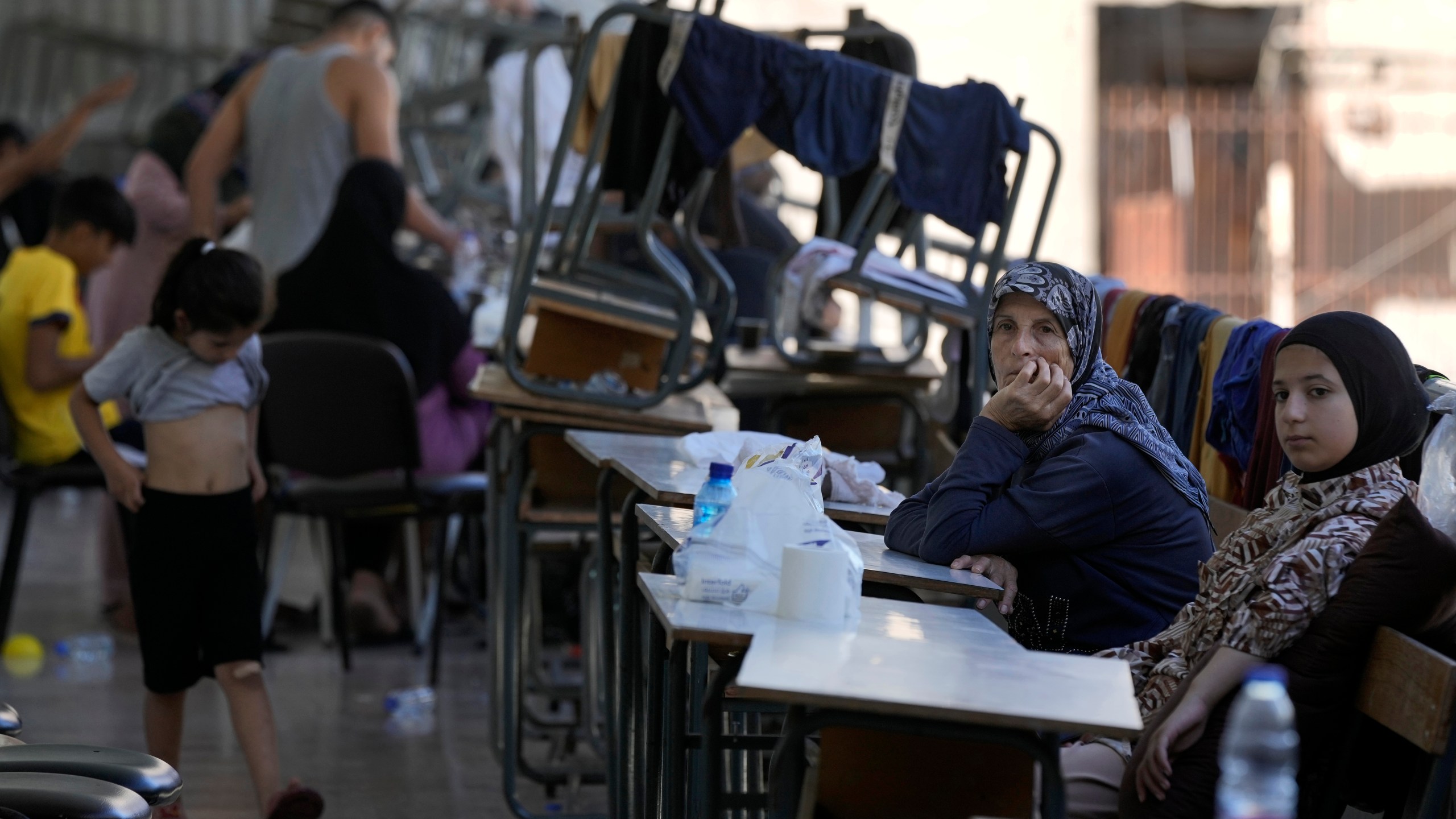 Displaced women and children sit in a classroom in Beirut, after fleeing the Israeli airstrikes in the south, Thursday, Sept. 26, 2024. (AP Photo/Bilal Hussein)