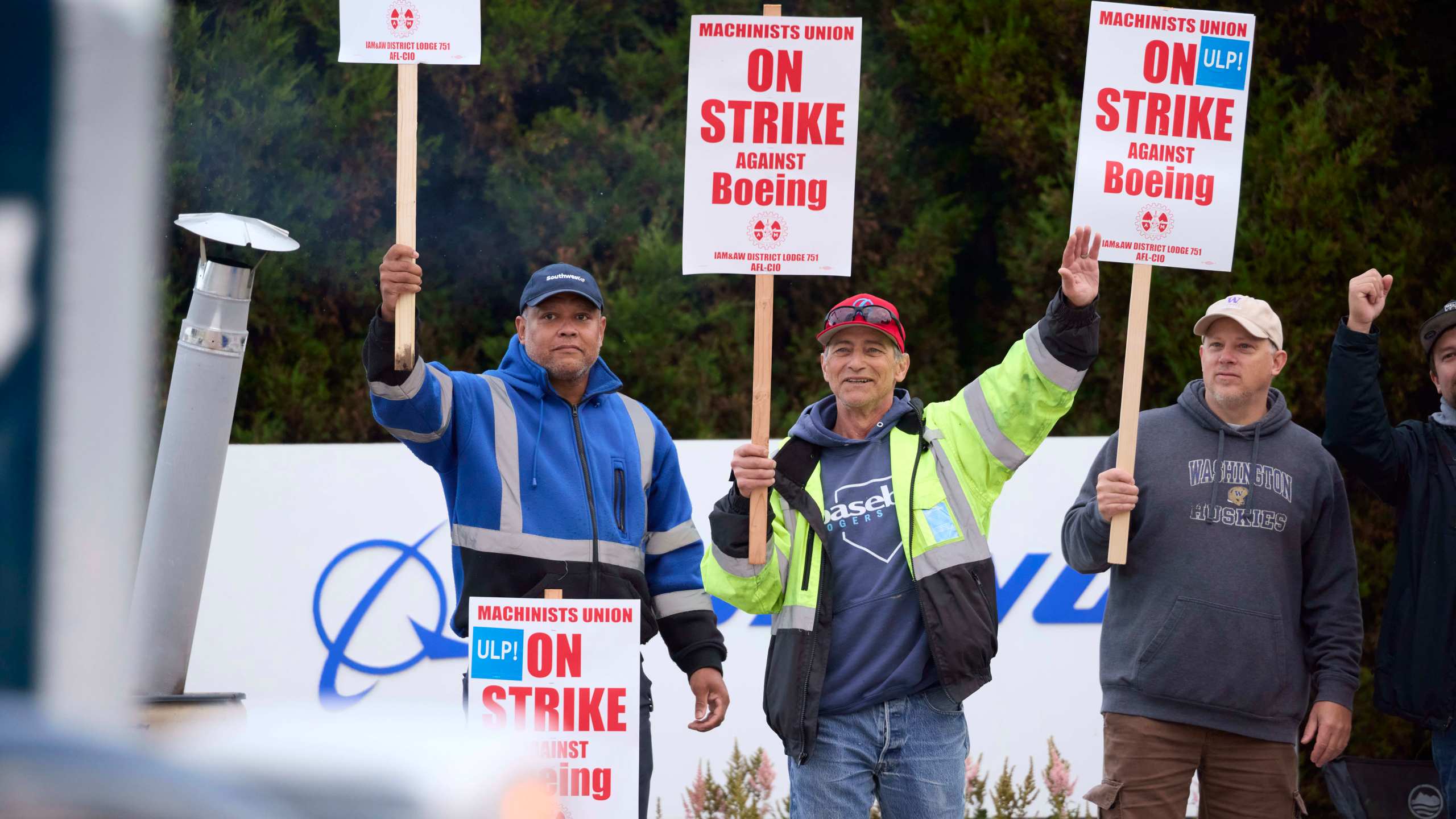 Boeing Machinists Union members Steven Wilson, left, Dave Hendrickson, center,, and Mark Erickson, right, wave to passing traffic while on the picket line at the Renton assembly plant, Friday, Sept. 13, 2024, in Renton, Wash. (AP Photo/John Froschauer)