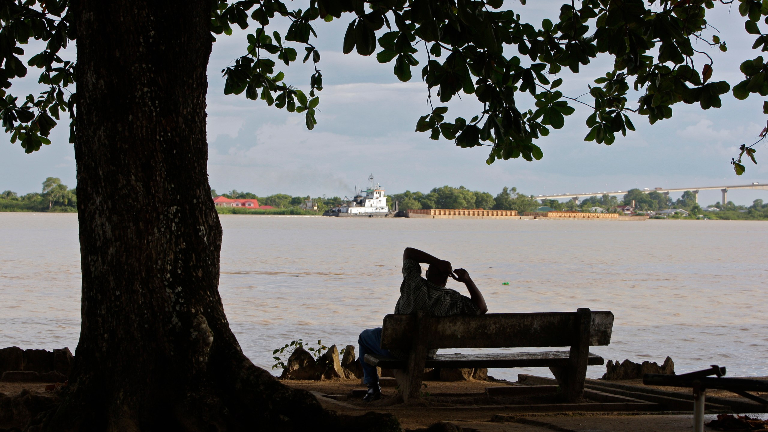 FILE - A man sits on the banks of the Suriname River in Paramaribo, Suriname, Aug. 10, 2010. (AP Photo/Andres Leighton, File)