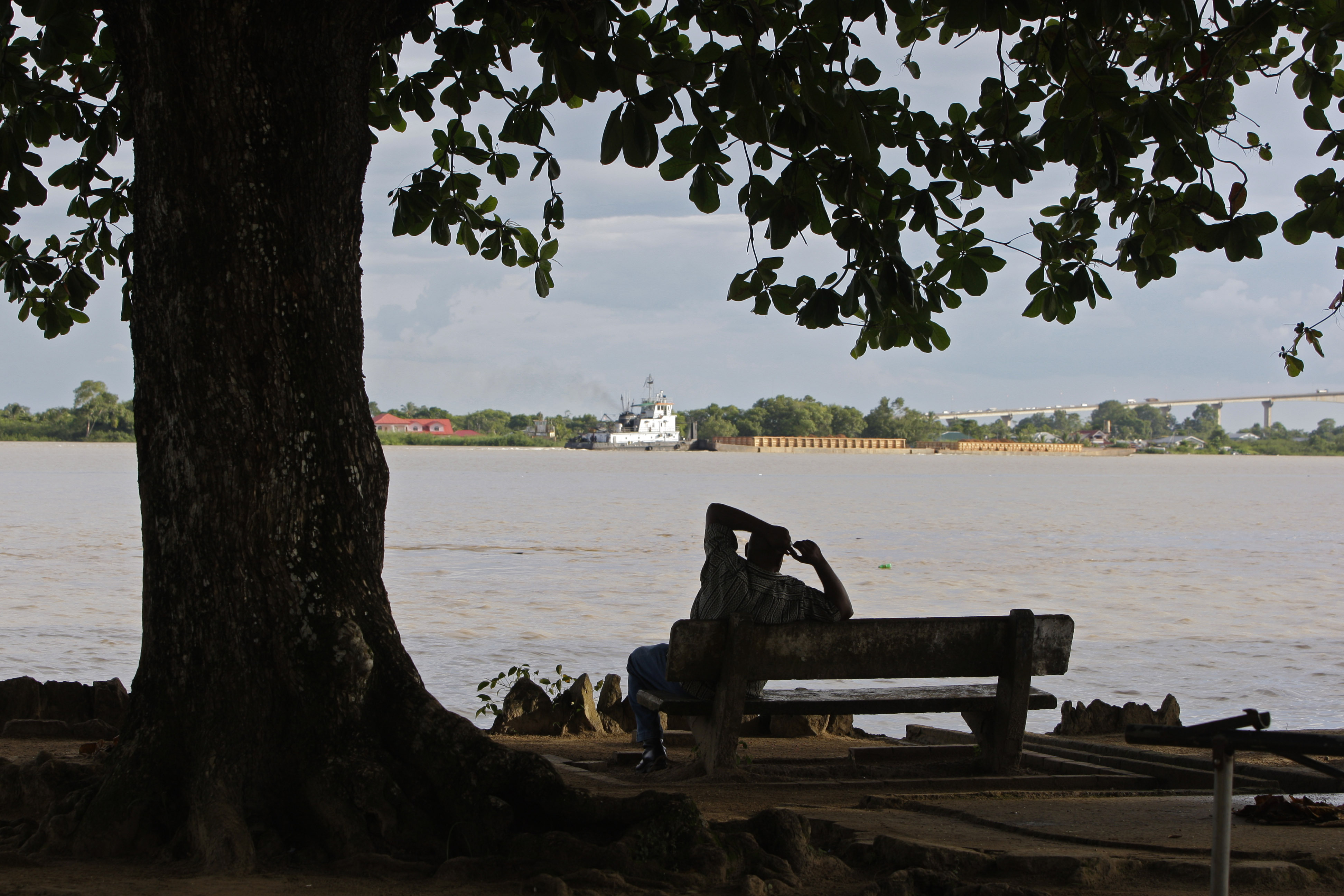 FILE - A man sits on the banks of the Suriname River in Paramaribo, Suriname, Aug. 10, 2010. (AP Photo/Andres Leighton, File)