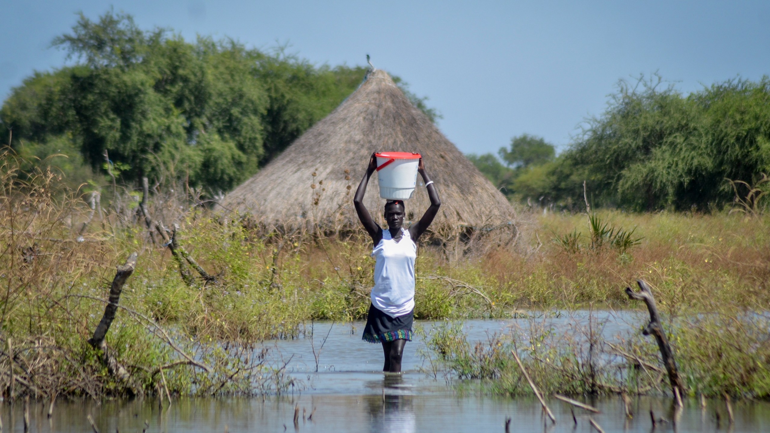 FILE - A woman carries a bucket on her head as she wades through floodwaters in the village of Wang Chot, Old Fangak county, Jonglei state, South Sudan, on Nov. 26, 2020. (AP Photo/Maura Ajak, File)