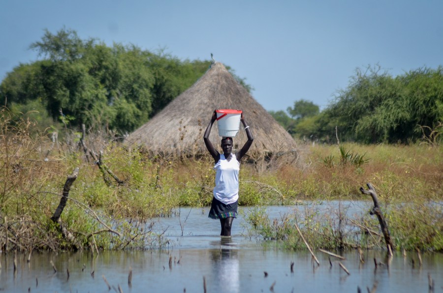 FILE - A woman carries a bucket on her head as she wades through floodwaters in the village of Wang Chot, Old Fangak county, Jonglei state, South Sudan, on Nov. 26, 2020. (AP Photo/Maura Ajak, File)