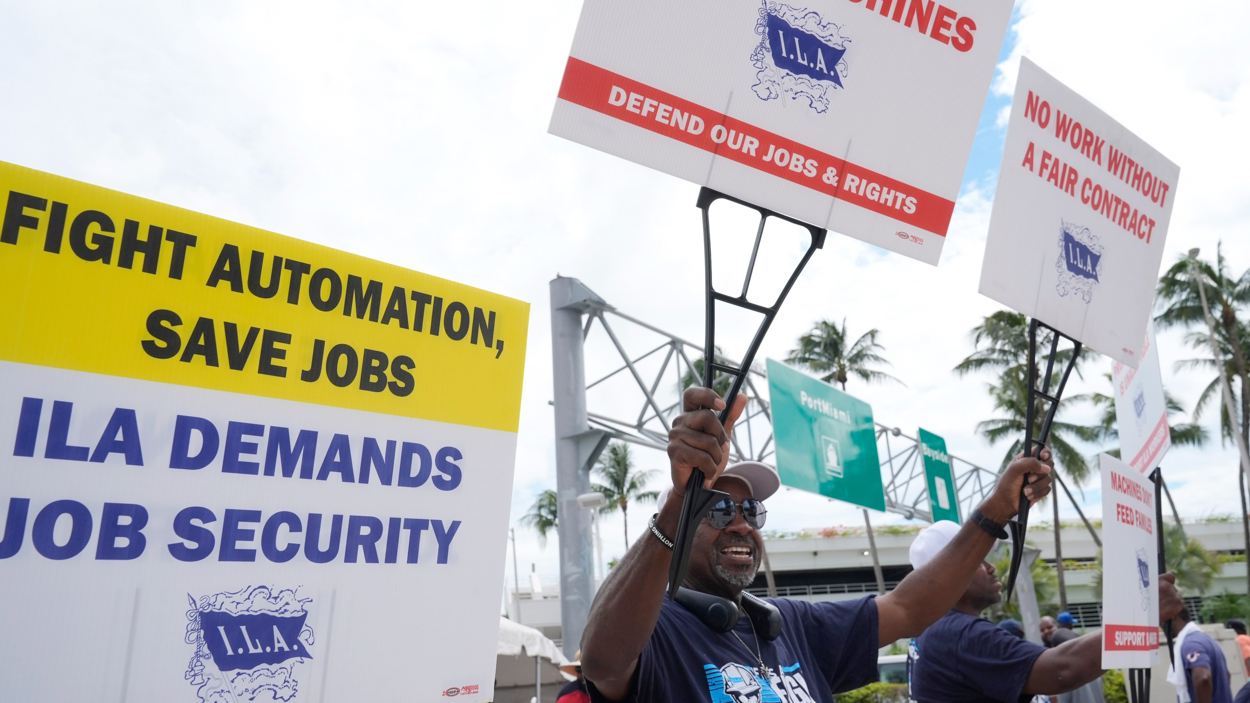 Dockworkers from Port Miami display signs at a picket line, Thursday, Oct. 3, 2024, in Miami. (AP Photo/Marta Lavandier)