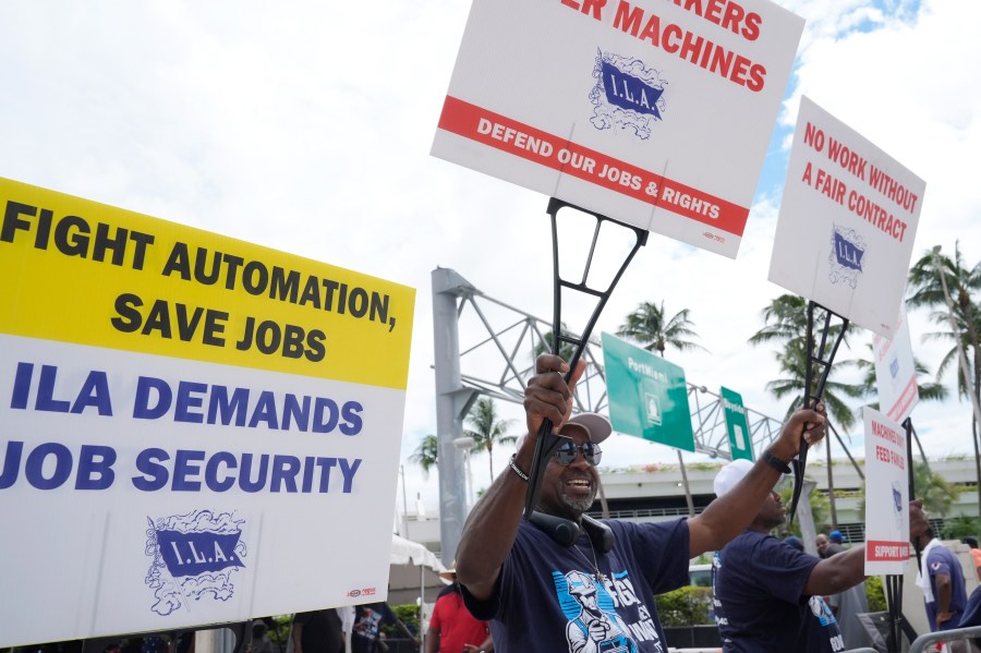 Dockworkers from Port Miami display signs at a picket line, Thursday, Oct. 3, 2024, in Miami. (AP Photo/Marta Lavandier)