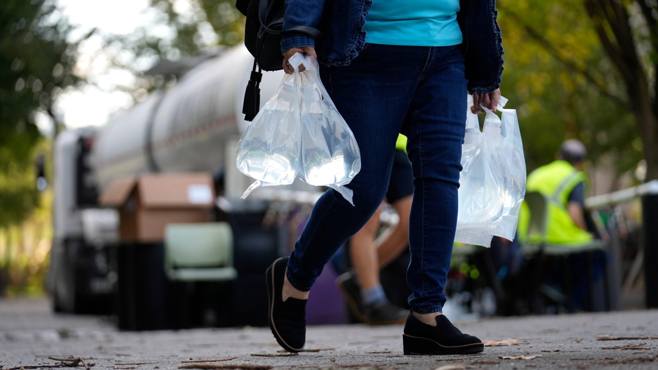 A person carries bags of fresh water after filling up from a tanker at a distribution site in the aftermath of Hurricane Helene Wednesday, Oct. 2, 2024, in Asheville, N.C. (AP Photo/Jeff Roberson)