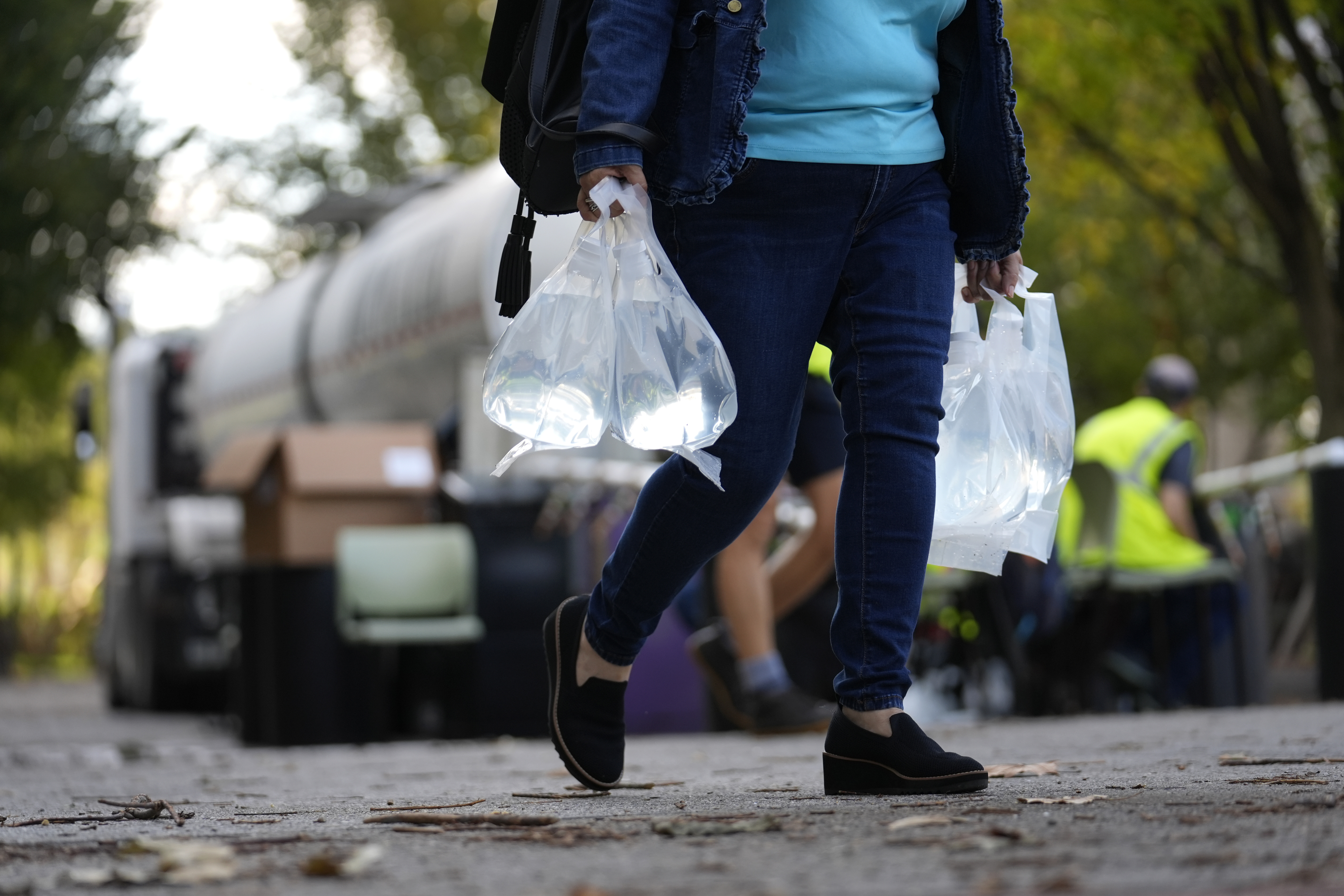 A person carries bags of fresh water after filling up from a tanker at a distribution site in the aftermath of Hurricane Helene Wednesday, Oct. 2, 2024, in Asheville, N.C. (AP Photo/Jeff Roberson)