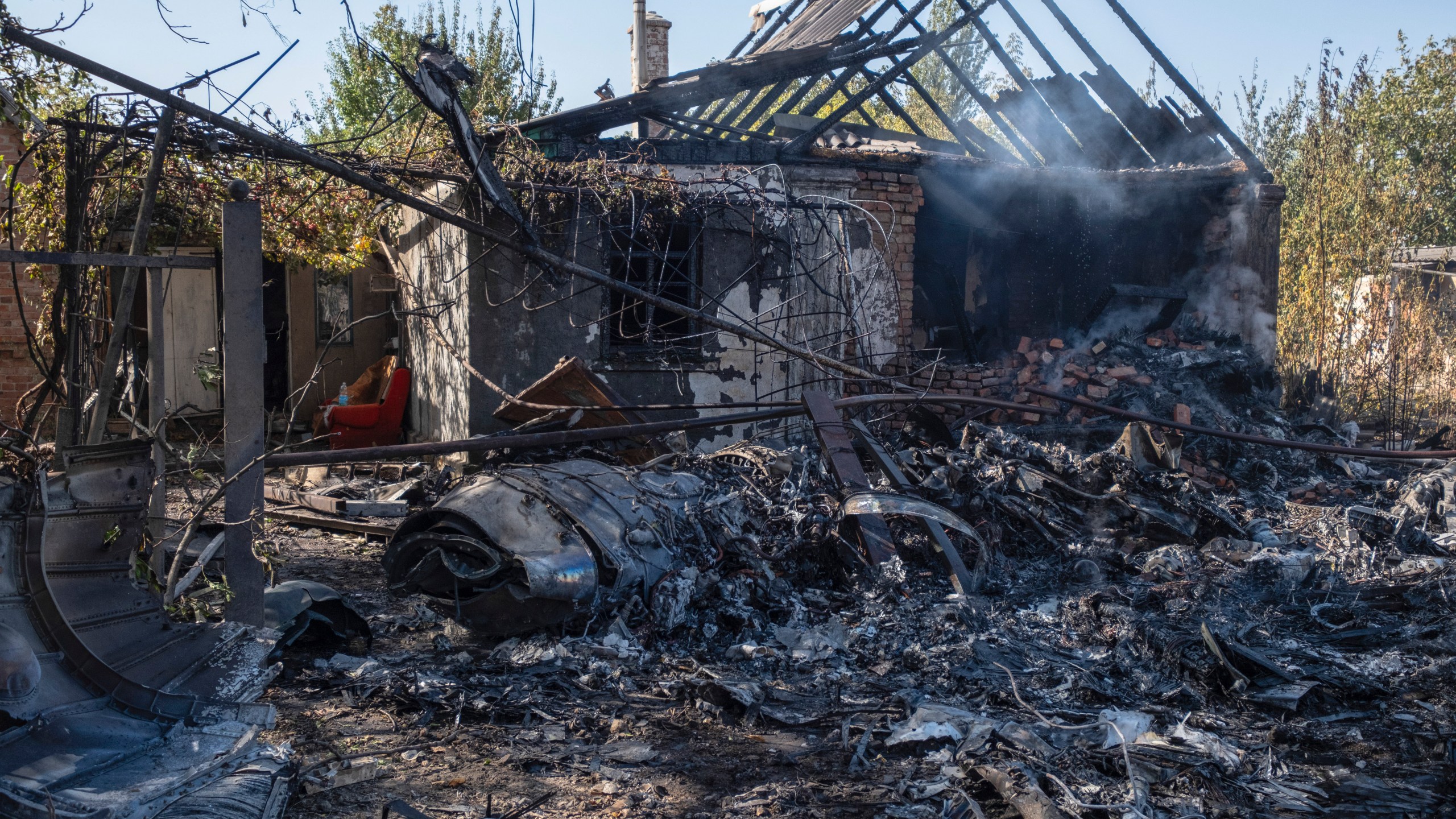 A damaged private house is seen in the background of fragments of a Russian military plane that was shot down, on the outskirts of Kostyantynivka, a near-front line city in the Donetsk region, Ukraine, Saturday, Oct. 5, 2024. (Iryna Rybakova via AP)