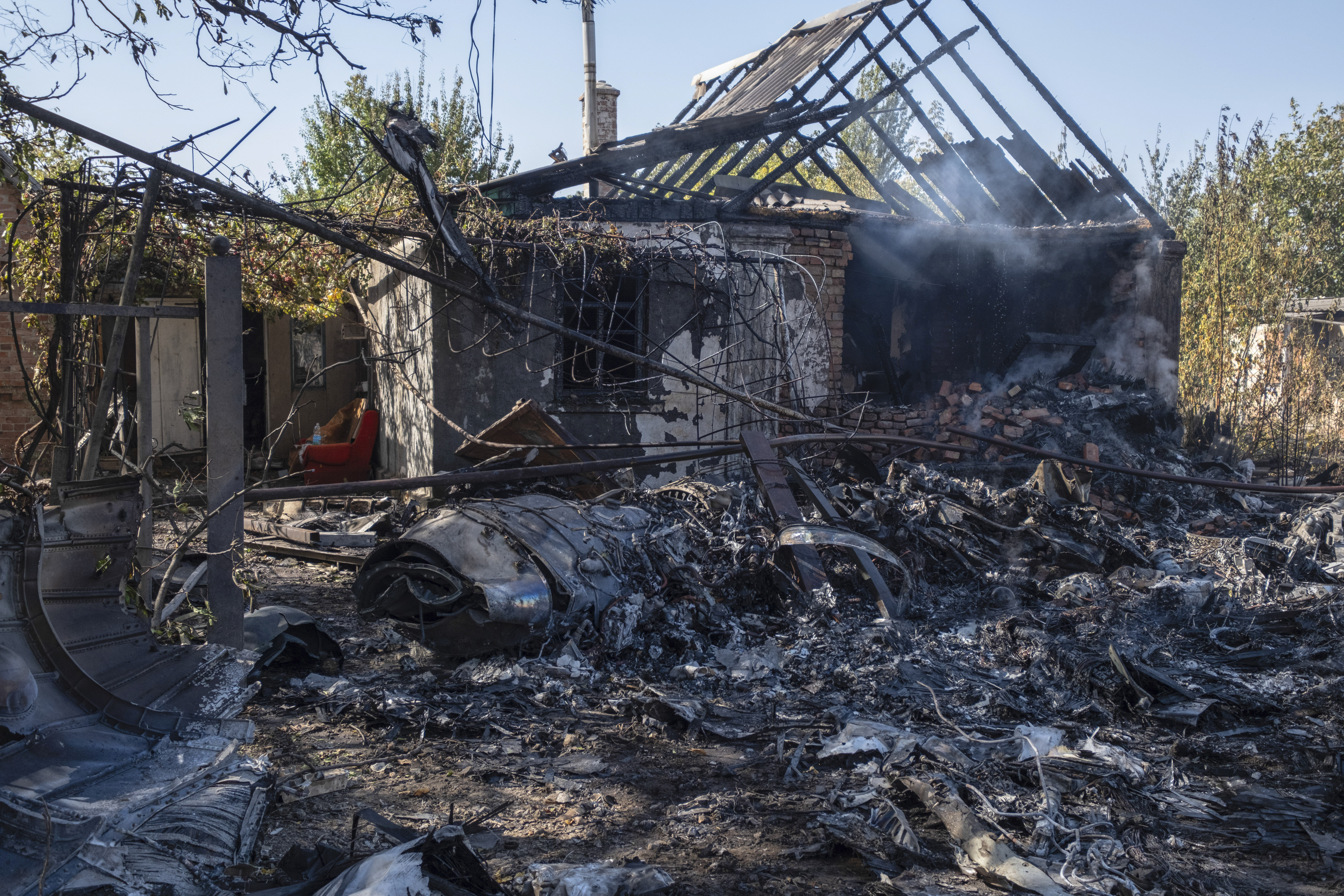 A damaged private house is seen in the background of fragments of a Russian military plane that was shot down, on the outskirts of Kostyantynivka, a near-front line city in the Donetsk region, Ukraine, Saturday, Oct. 5, 2024. (Iryna Rybakova via AP)