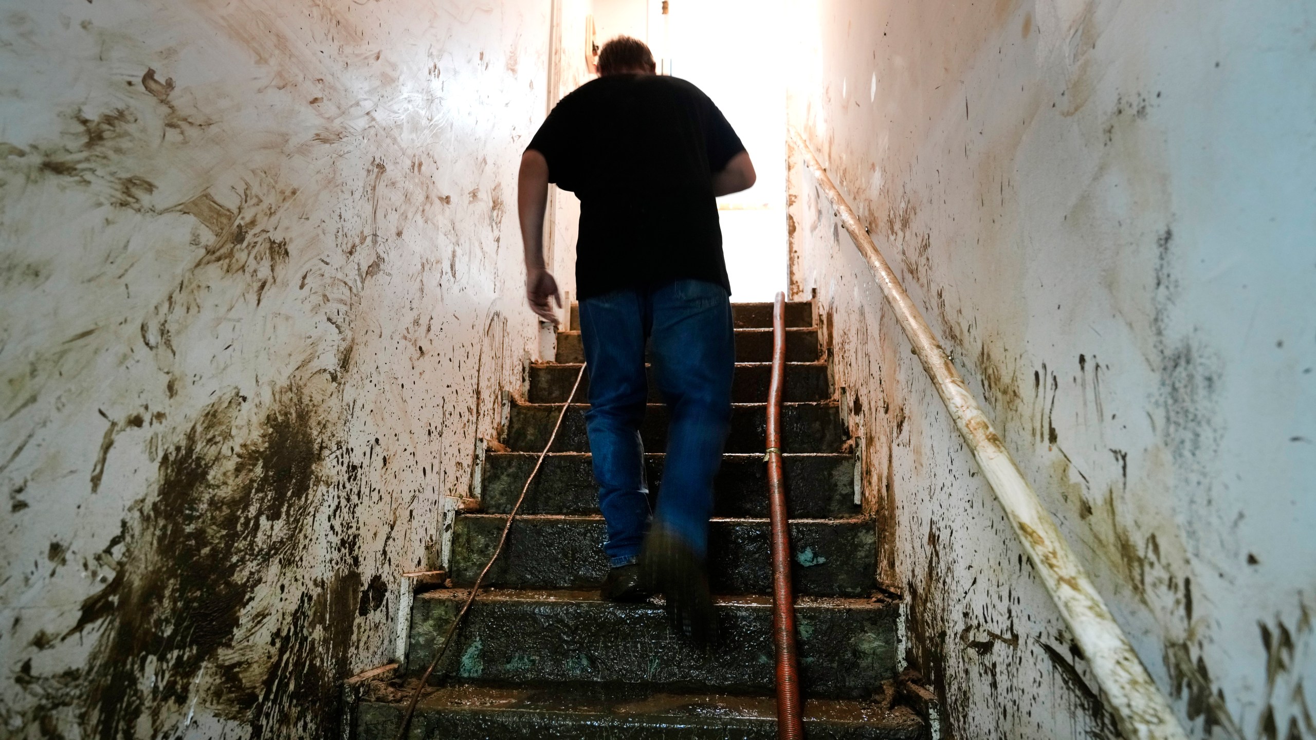 Contractor Joshua Taylor walks up stairs covered in mud leading to the basement of a funeral home that was flooded in the aftermath of Hurricane Helene while working to clean up the building Saturday, Oct. 5, 2024, in Newport, Tenn. (AP Photo/Jeff Roberson)