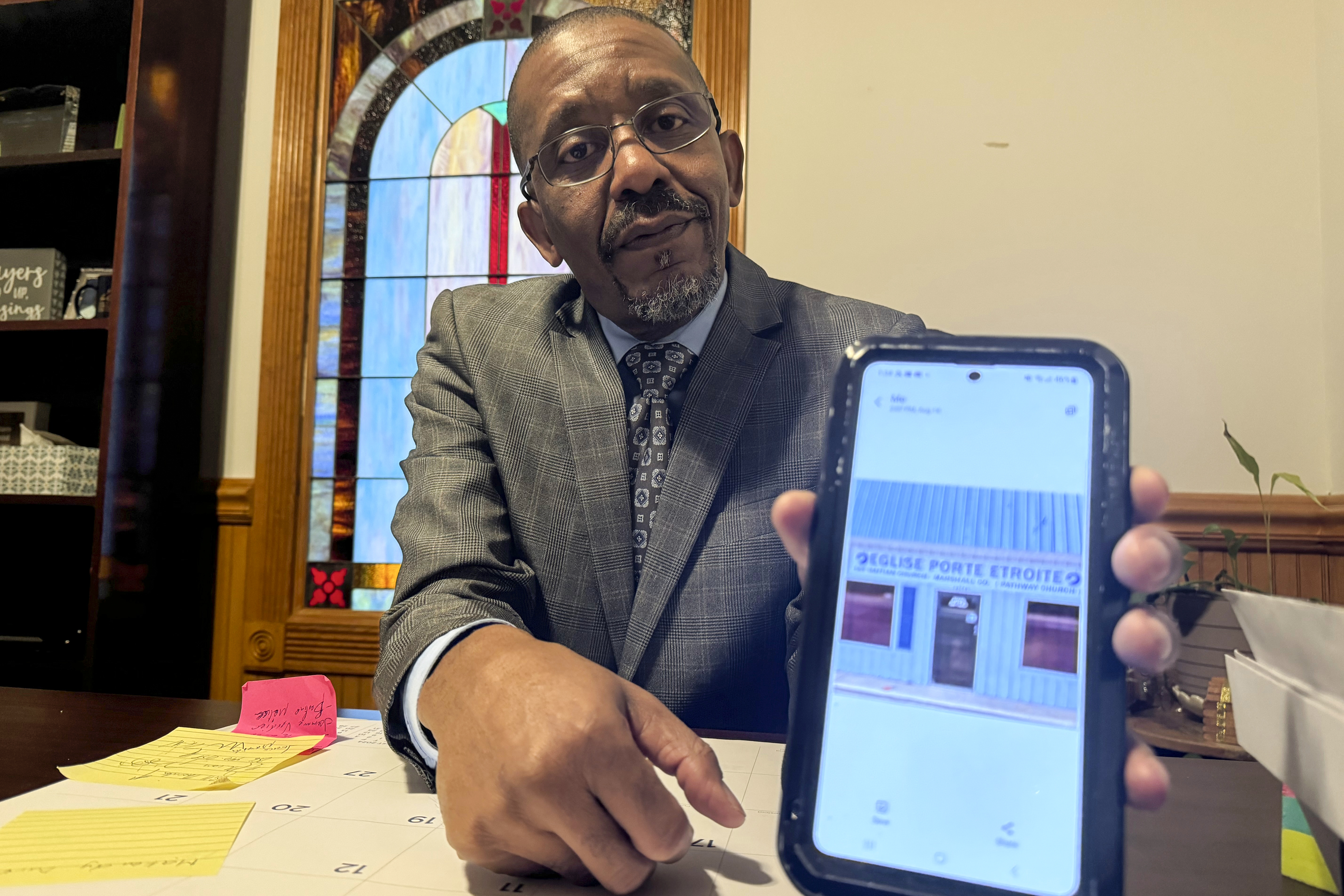 Pastor John Pierre-Charles shows a picture of the original building where the Eglise Porte Etroite church met when he first started it in 2010, in Albertville, Ala., Sept. 29, 2024. (AP Photo/Safiyah Riddle)