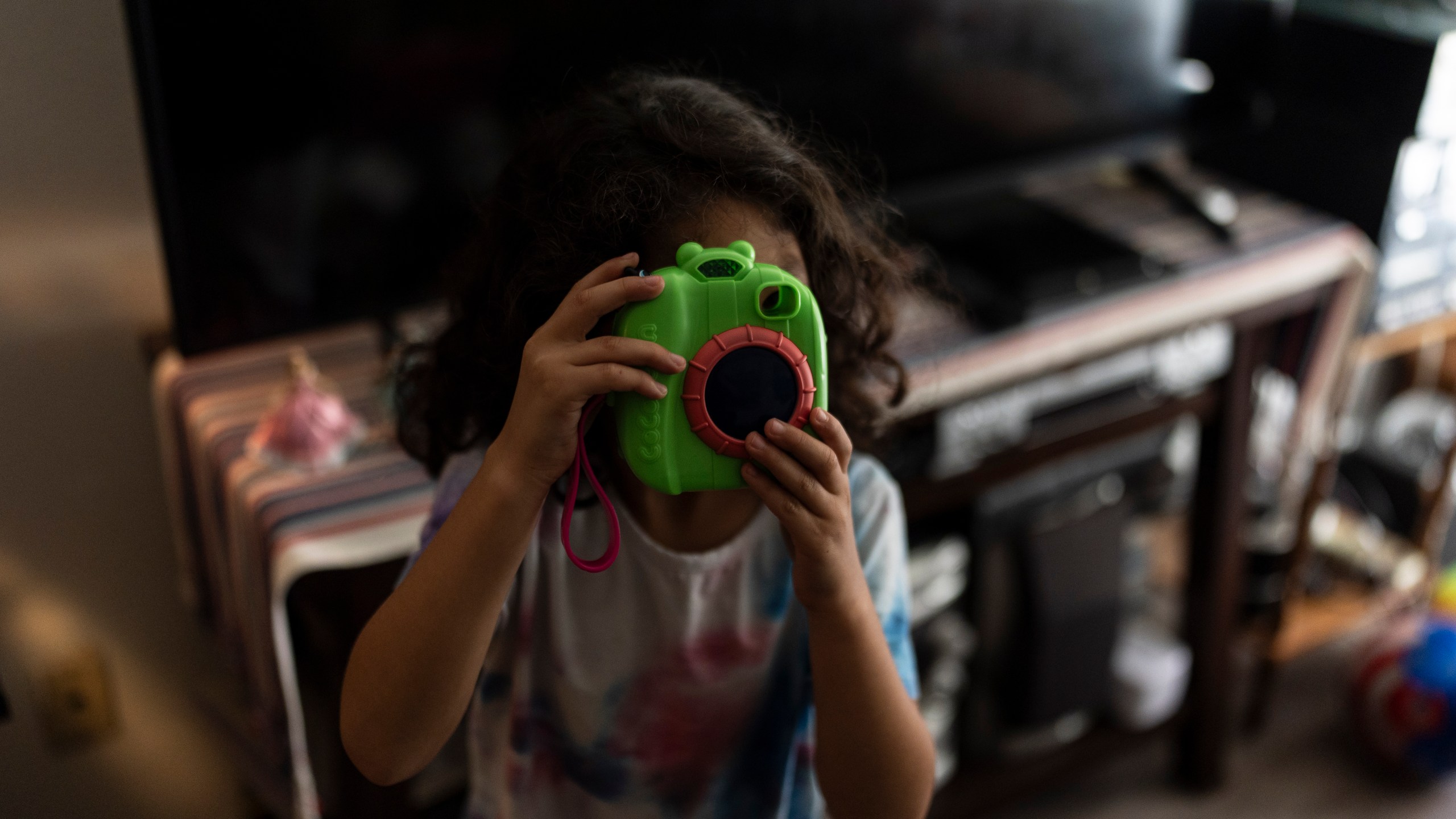 Rubie Caceres, a granddaughter of Marina Maalouf, a longtime resident of Hillside Villa, plays with a toy camera in her apartment in Los Angeles, Tuesday, Oct. 1, 2024. (AP Photo/Jae C. Hong)