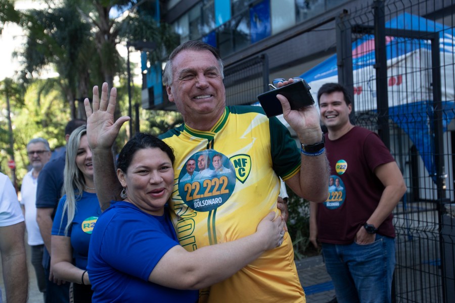 A supporter hugs former Brazilian President Jair Bolsonaro, center, as he supports for Rio de Janeiro mayoral candidate Alexandre Ramagem during municipal elections in Rio de Janeiro, Sunday, Oct. 6, 2024. (AP Photo/Bruna Prado)