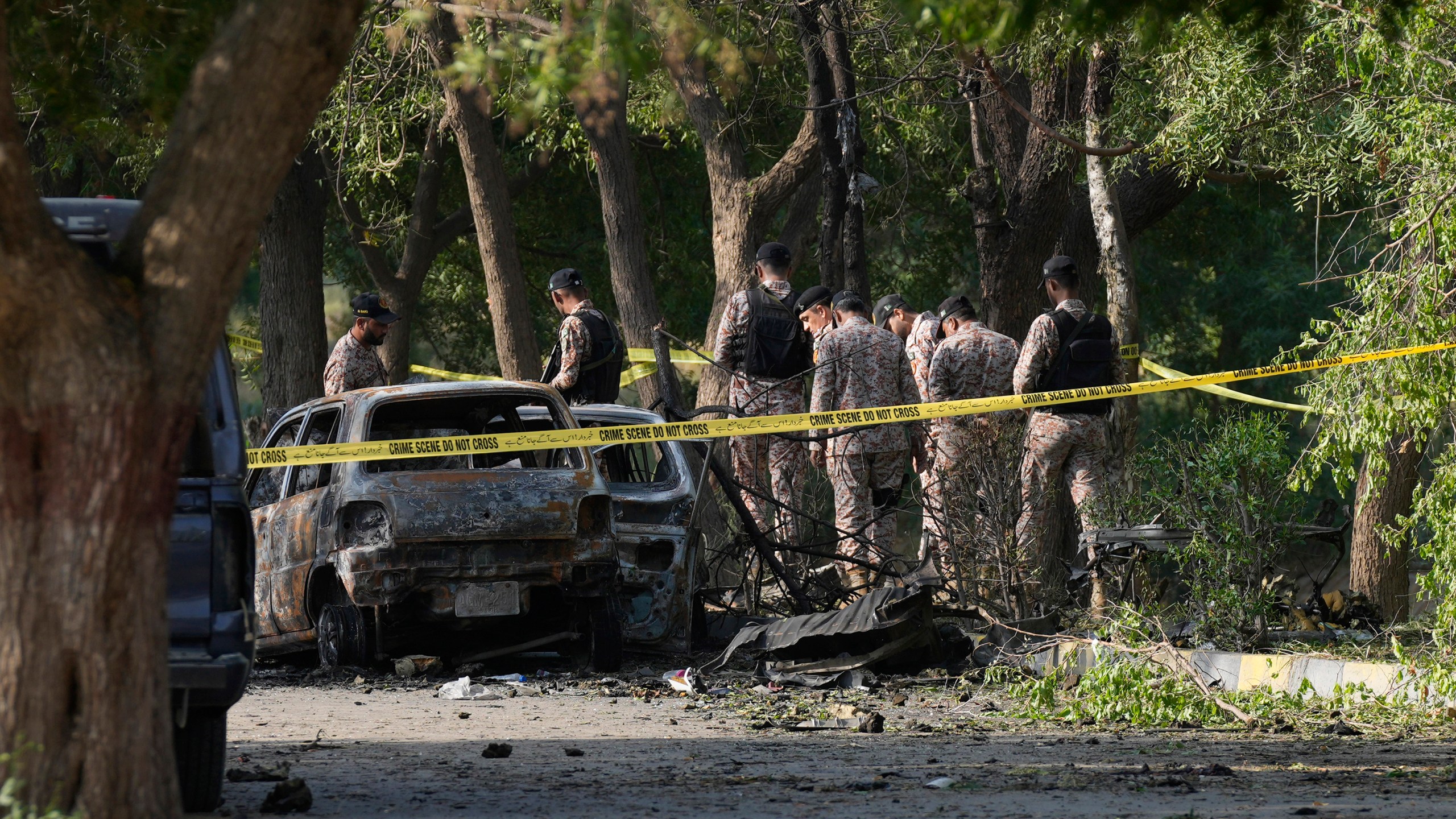 Security officials work on the site of an explosion that caused injures and destroyed vehicles outside the Karachi airport, Pakistan, Monday, Oct. 7, 2024. Pakistani Baloch separatists claim deadly bomb attack that killed 2 Chinese near Karachi airport. (AP Photo/Fareed Khan)