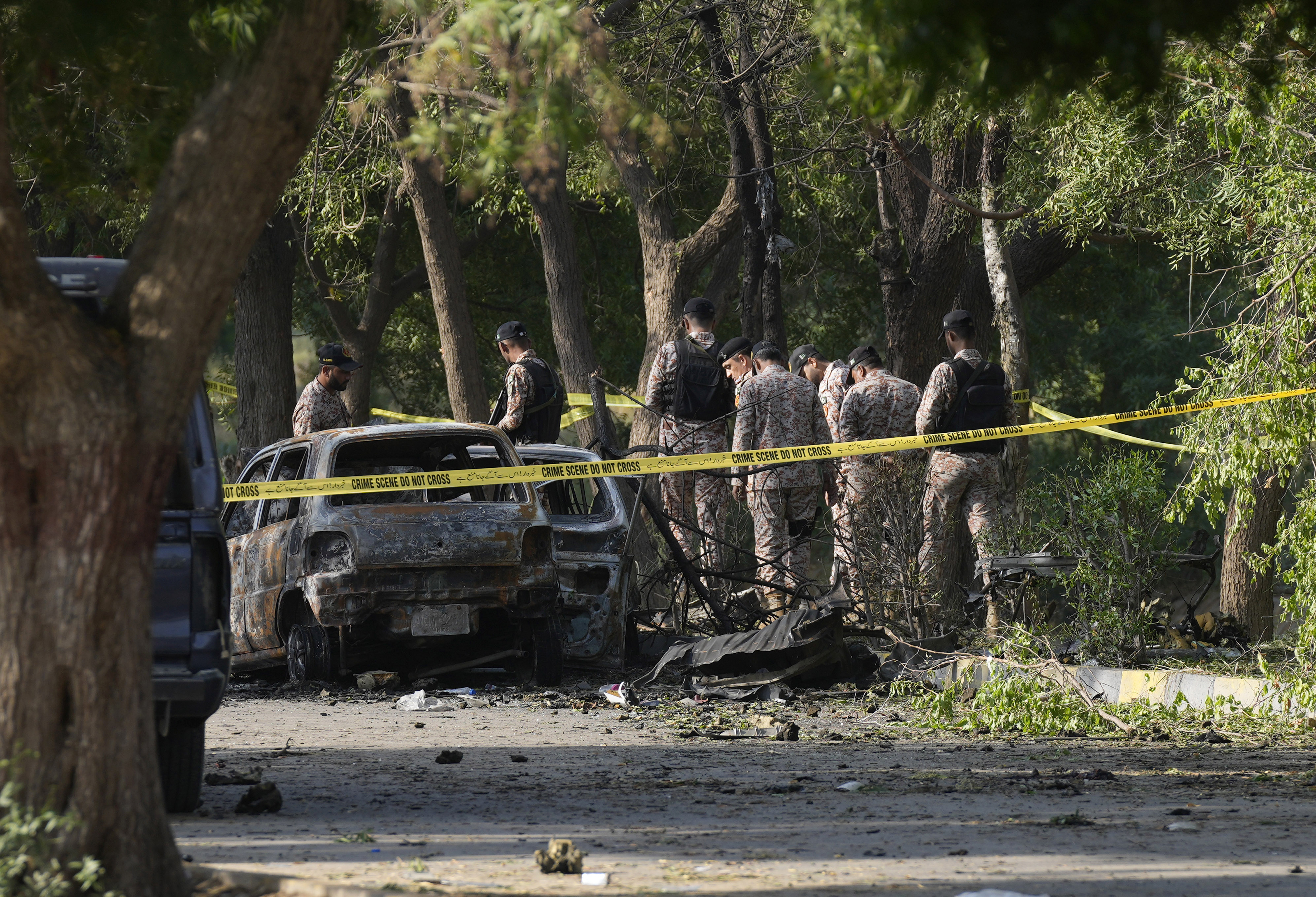 Security officials work on the site of an explosion that caused injures and destroyed vehicles outside the Karachi airport, Pakistan, Monday, Oct. 7, 2024. Pakistani Baloch separatists claim deadly bomb attack that killed 2 Chinese near Karachi airport. (AP Photo/Fareed Khan)