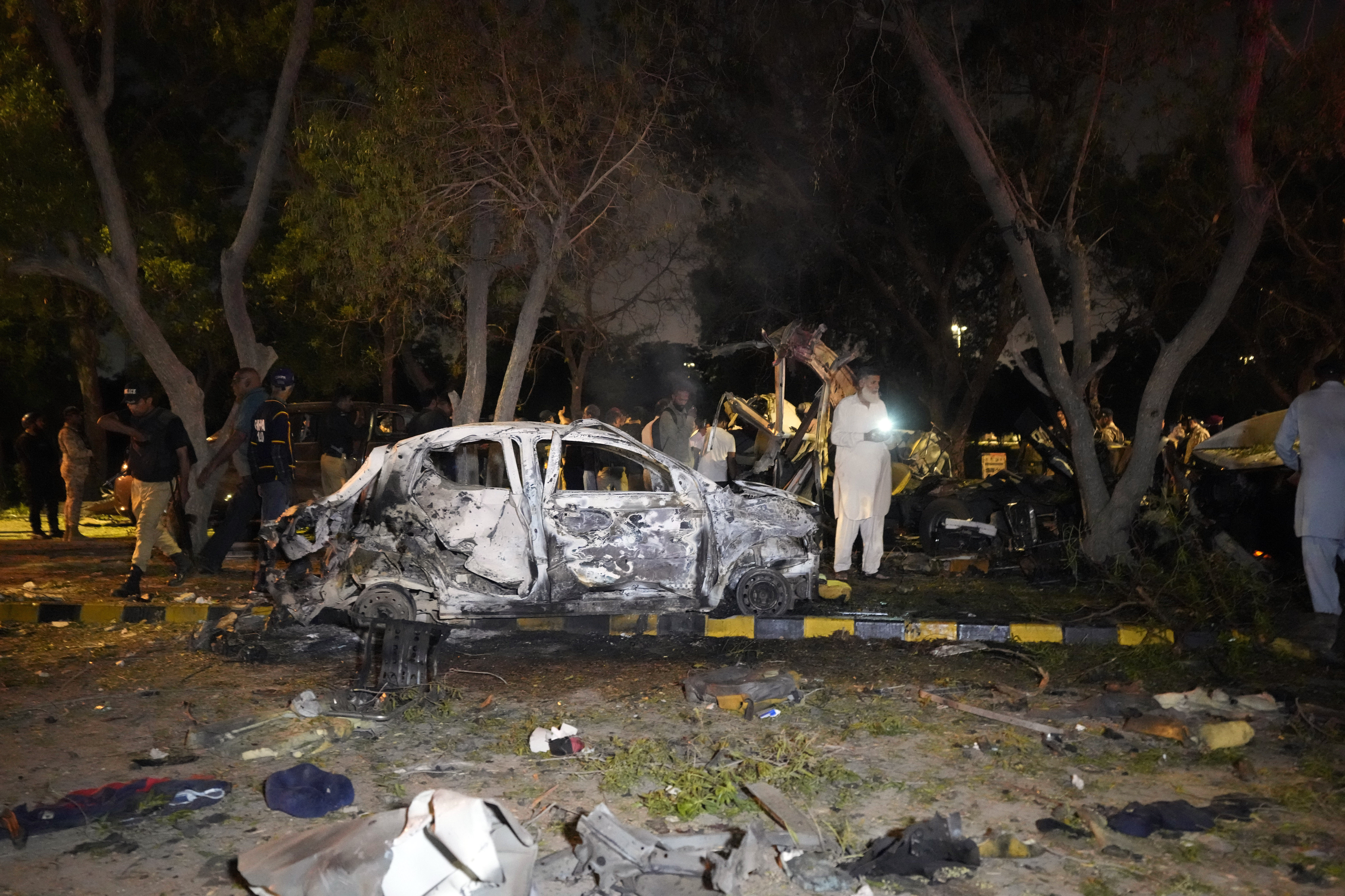 Security officials examine the site of an explosion that caused injures and destroyed vehicles outside the Karachi airport, Pakistan, early Monday, Oct. 7, 2024. (AP Photo/Fareed Khan)