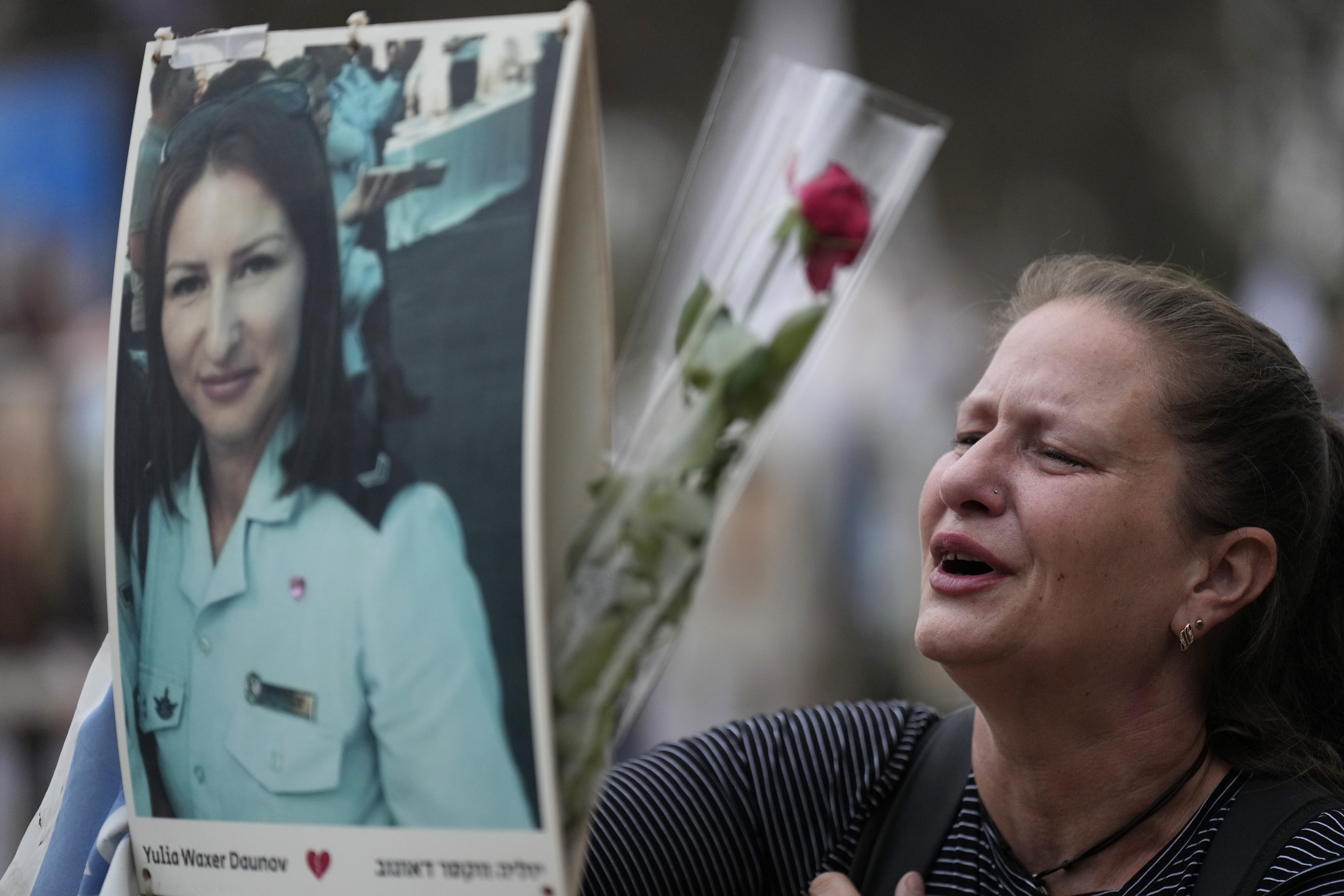 Victoria stands in front a picture of her sister, Yulia Waxer Daunt, as she visits the site of the Nova music festival, where hundreds of revelers were killed and abducted by Hamas and taken into Gaza, on the one-year anniversary of the attack, near Kibbutz Reim, southern Israel, Monday, Oct. 7, 2024. (AP Photo/Ariel Schalit)