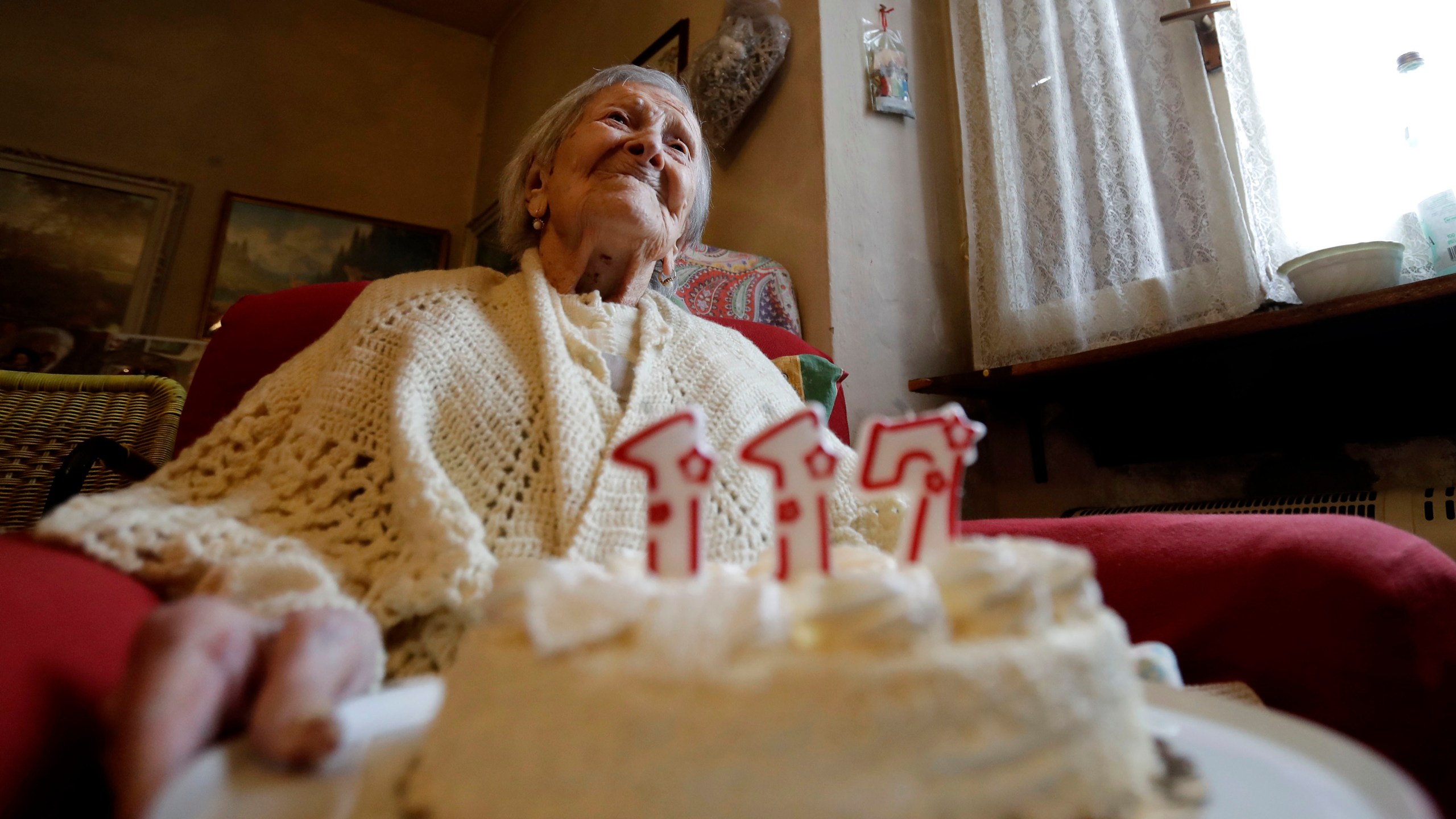 FILE- Emma Morano holds a cake with candles marking 117 years on the day of her birthday, Nov. 29, 2016, in Verbania, Italy. (AP Photo/Antonio Calanni)