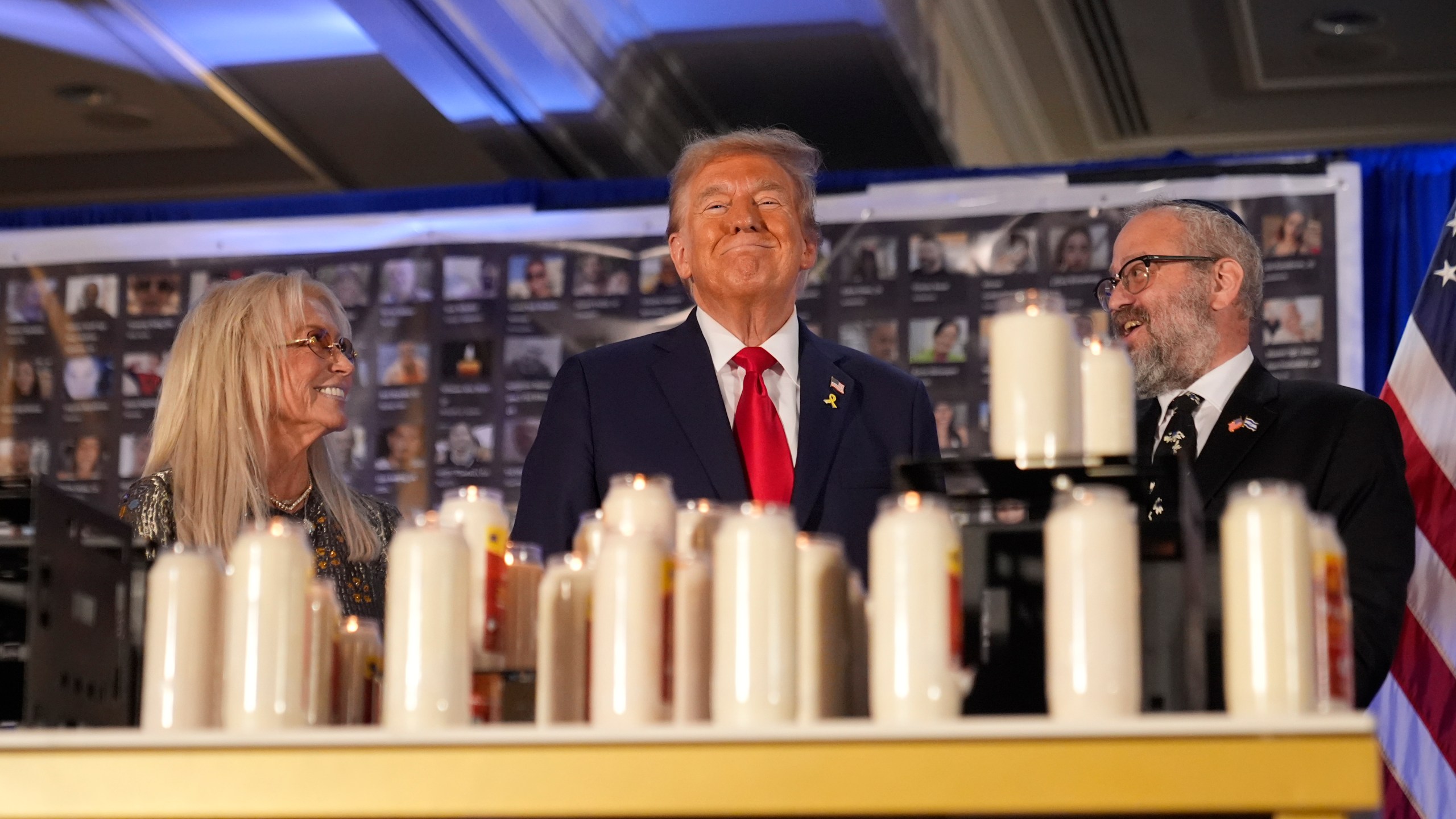 Republican presidential nominee former President Donald Trump stands with Miriam Adelson and Rabbi Yeshuda Kaploun at an event marking one year since the Oct. 7 Hamas attack on Israel, Monday, Oct. 7, 2024, in Miami. (AP Photo/Alex Brandon)