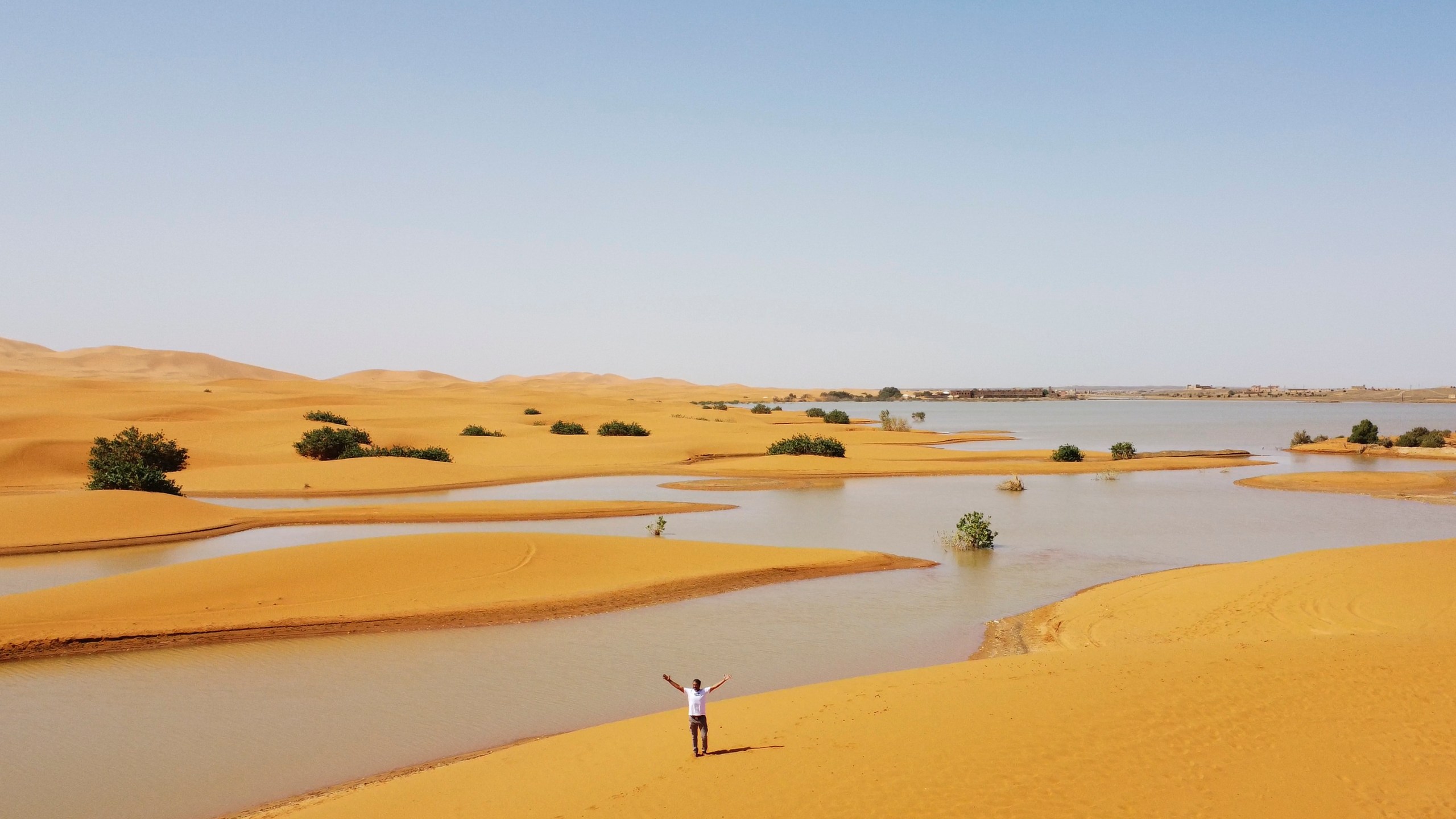 A man gestures as he walks on sand dunes next to a lake caused by heavy rainfall in the desert town of Merzouga, near Rachidia, southeastern Morocco, Wednesday, Oct. 2, 2024. (AP Photo)