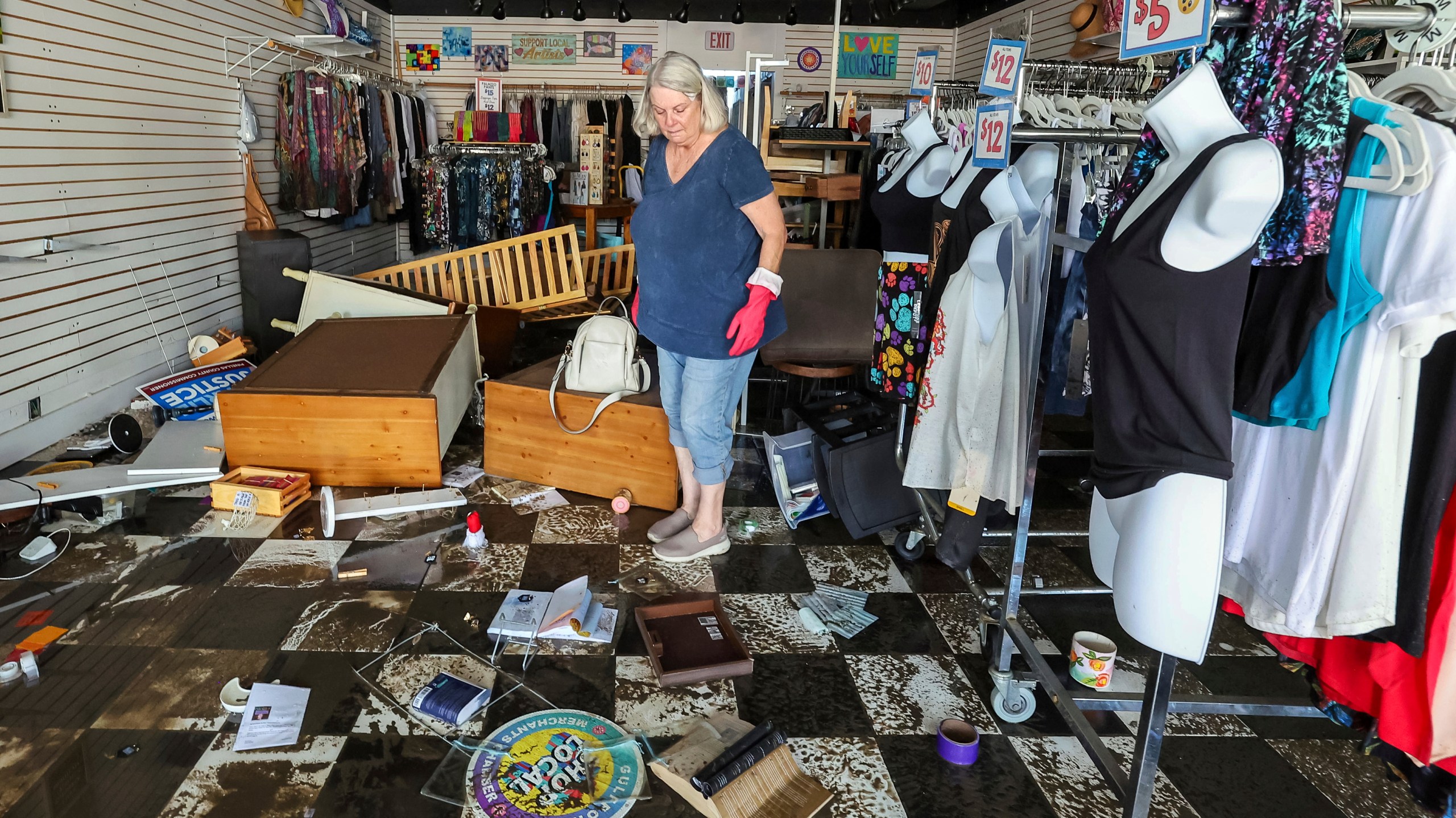 FILE - Jill Rice looks over the damage to her store caused by flooding from Hurricane Helene, Sept. 27, 2024, in Gulfport, Fla. (AP Photo/Mike Carlson, File)