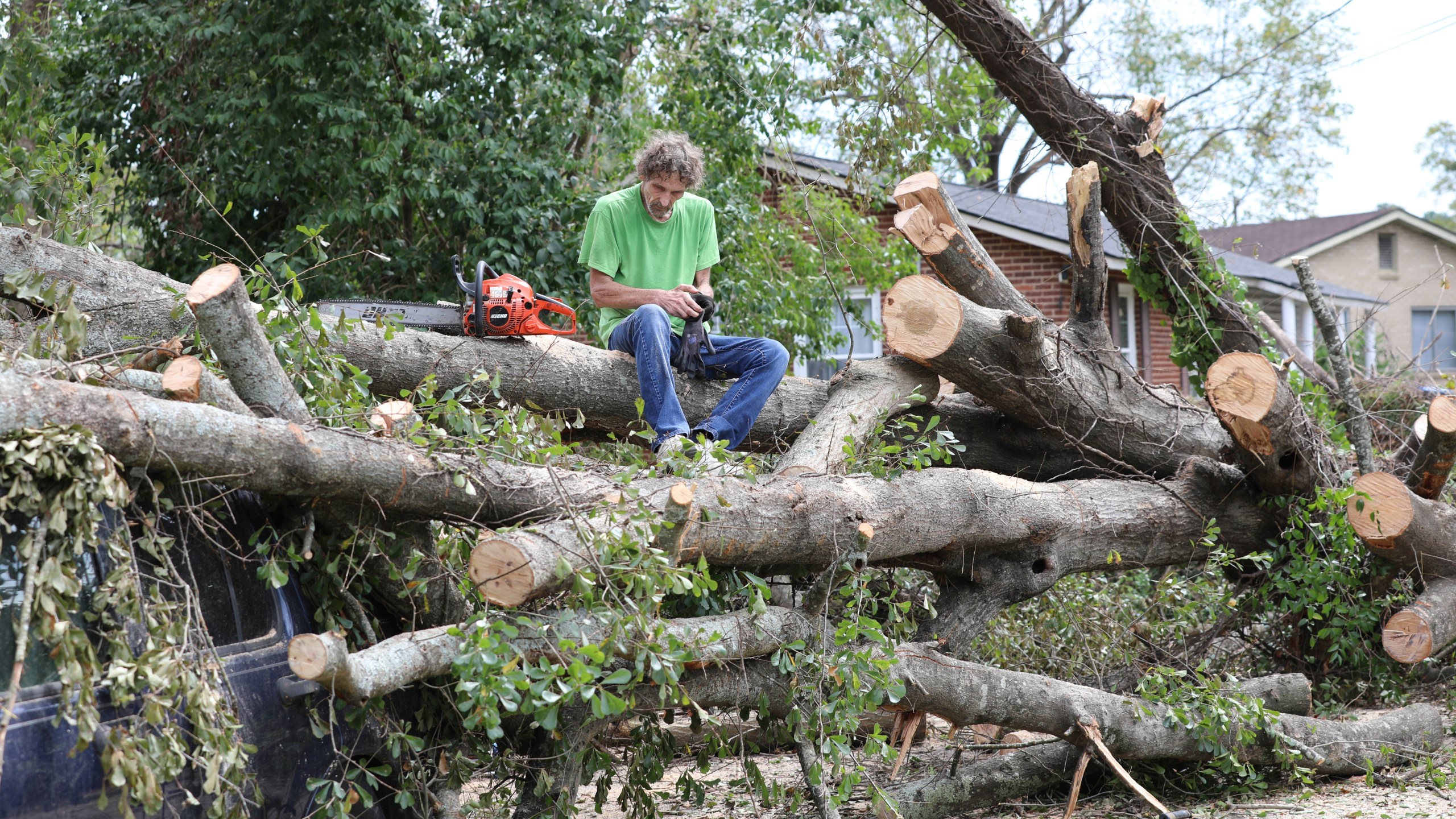 Andy Brown takes a break on top of what remains of a tree that destroyed his SUV when it fell during Hurricane Helene on in Augusta, Ga., Tuesday, Oct. 1, 2024. (AP Photo/Jeffrey Collins)