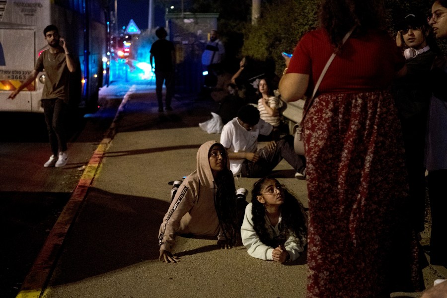 FILE - Israelis wait to re-board their bus after projectiles were launched from Iran are being intercepted in the skies over in Rosh HaAyin, Israel, Tuesday, Oct. 1, 2024. (AP Photo/Maya Alleruzzo, File)