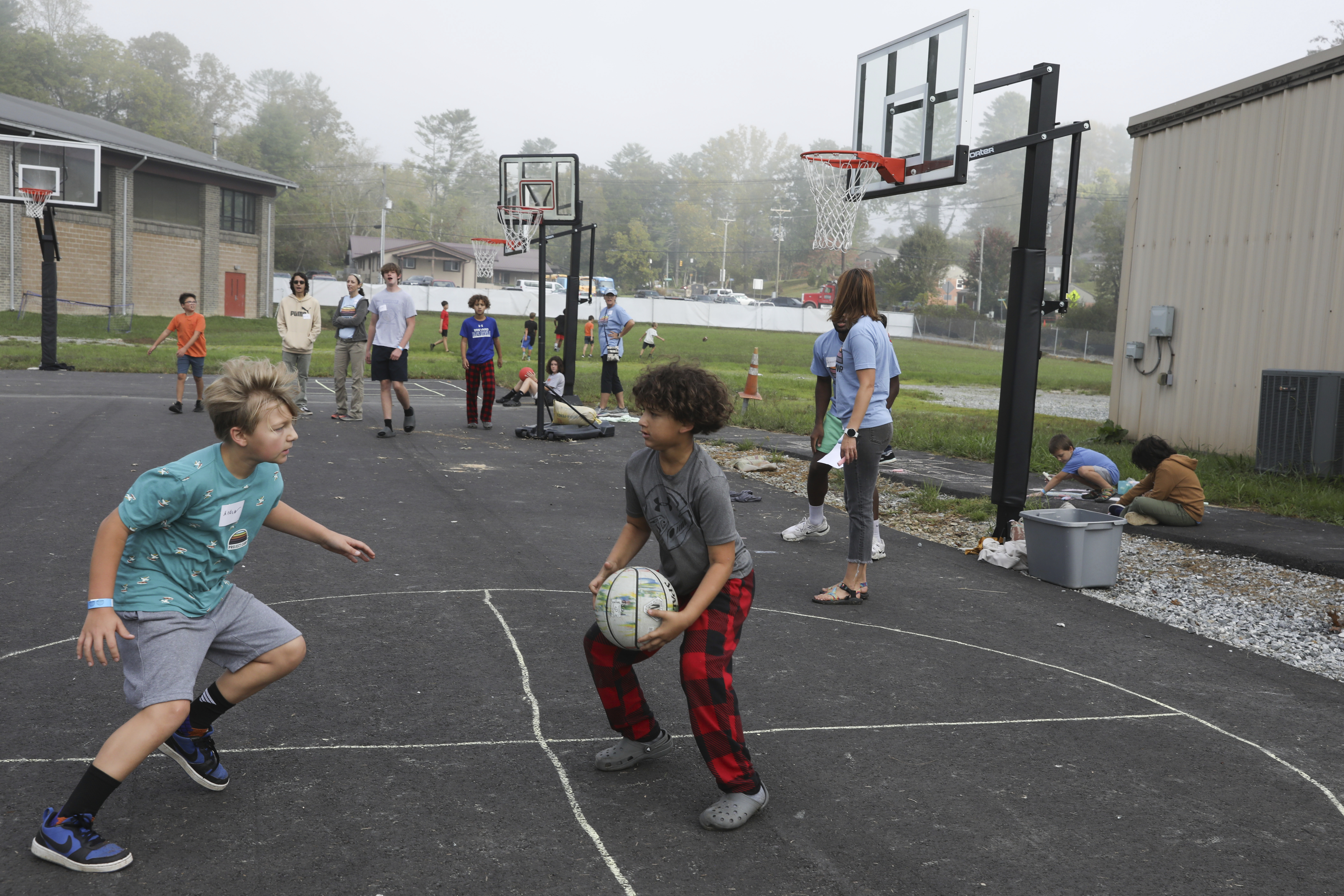 Boys play basketball at the Project:Camp pop-up daycamp for families impacted by Hurricane Helene in Brevard, N.C., Monday, Oct. 7, 2024. (AP Photo/Gabriela Aoun Angueira)