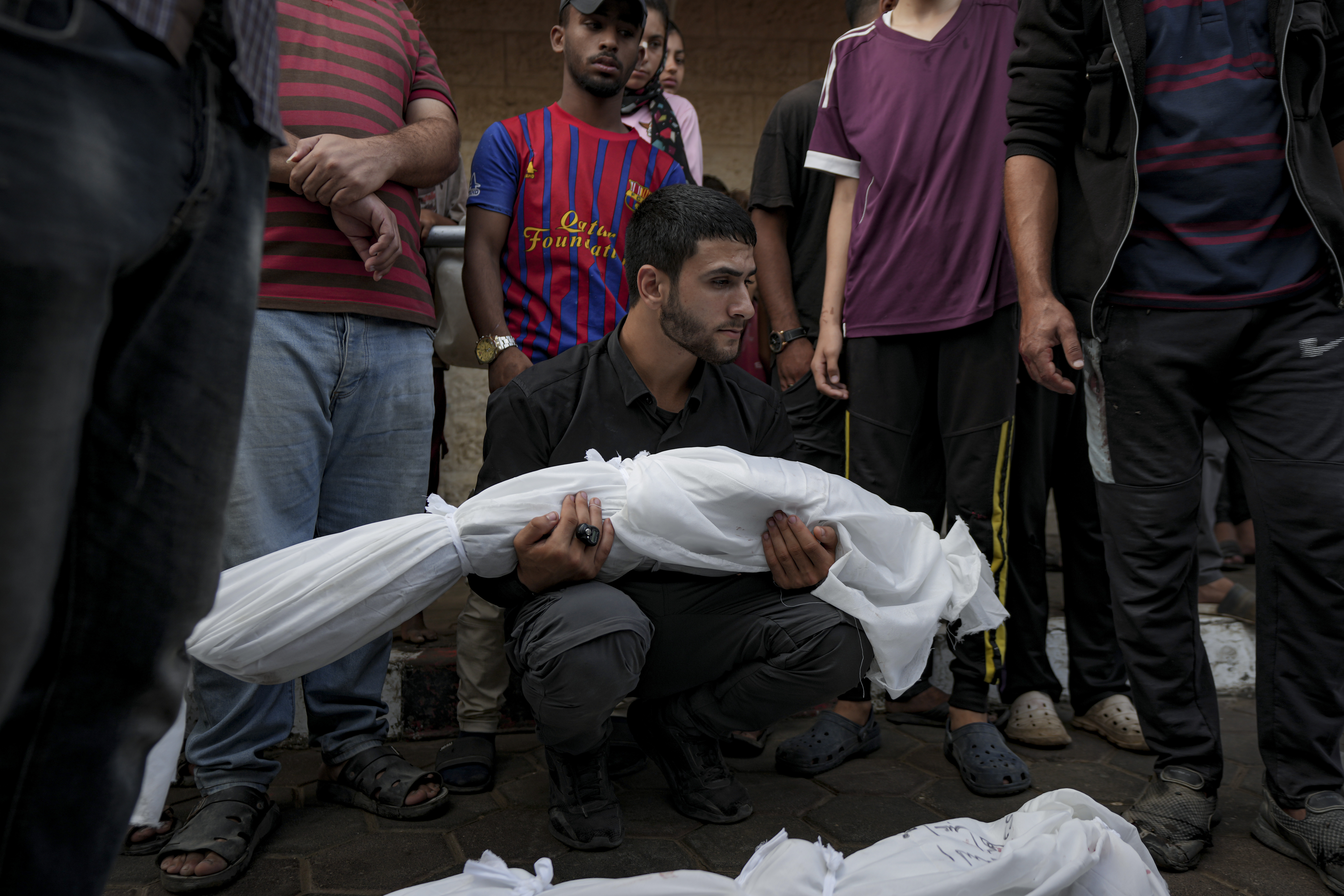 A Palestinian man holds the body of a relative killed in the Israeli bombardment of the Gaza Strip at a hospital morgue in Deir al-Balah, Tuesday, Oct. 8, 2024. (AP Photo/Abdel Kareem Hana)