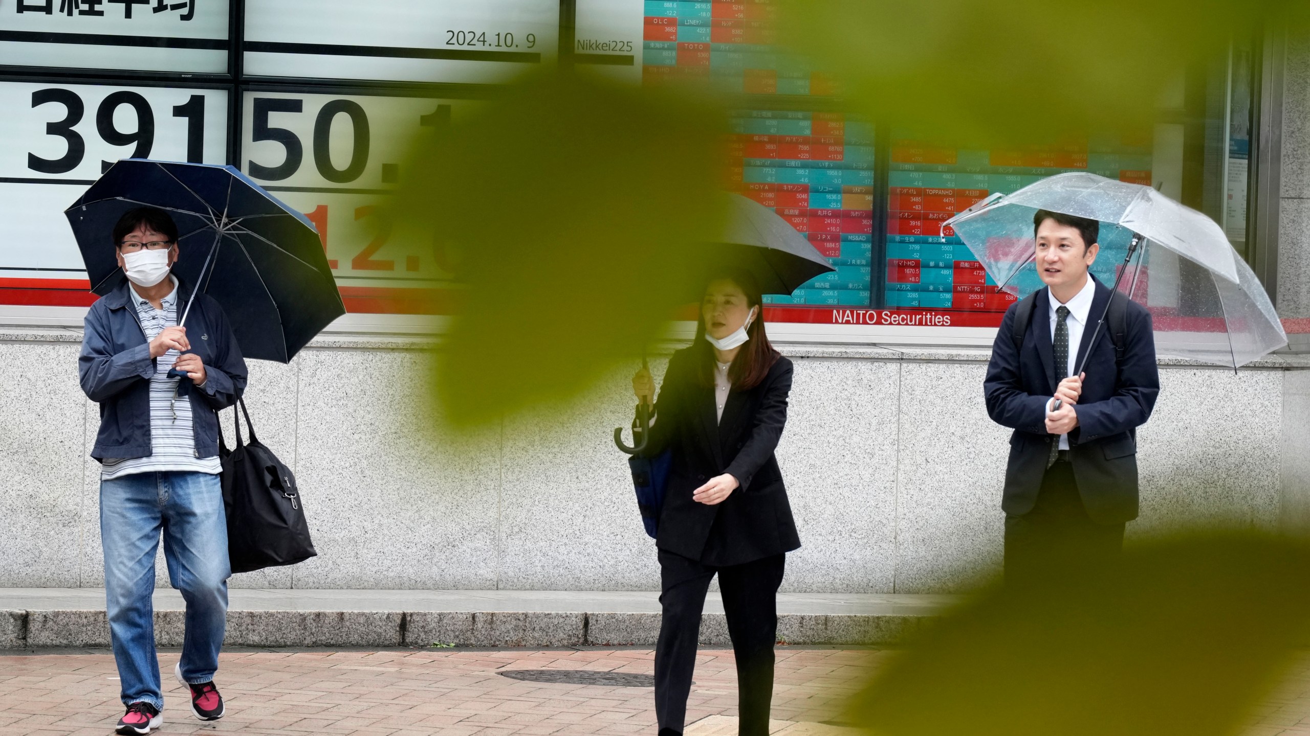 People walk in front of an electronic stock board showing Japan's Nikkei index at a securities firm, Wednesday, Oct. 9, 2024, in Tokyo. (AP Photo/Eugene Hoshiko)