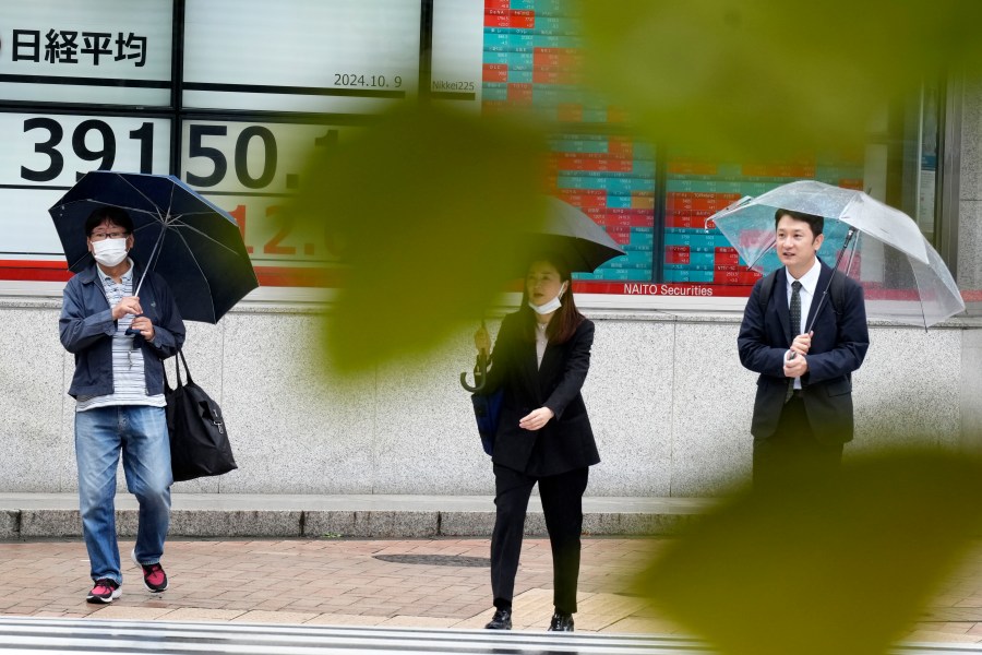 People walk in front of an electronic stock board showing Japan's Nikkei index at a securities firm, Wednesday, Oct. 9, 2024, in Tokyo. (AP Photo/Eugene Hoshiko)